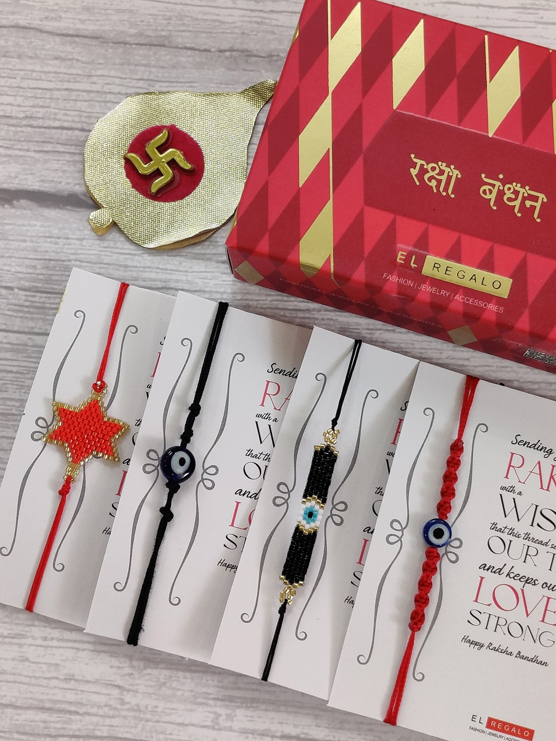 

EL REGALO Set Of 4 Red & Black Evil Eye Beaded Wrap Around Rakhi With Roli Chawal & Raksha Bandhan Greeting Card