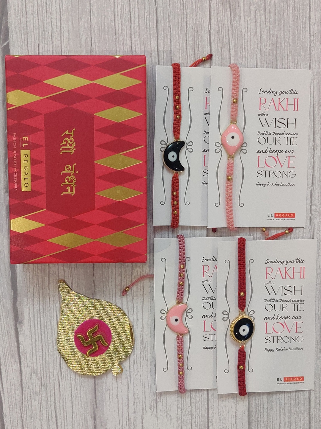 

EL REGALO Set Of 4 Red & Pink Evil Eye Wrap Around Rakhi With Roli Chawal & Raksha Bandhan Greeting Card