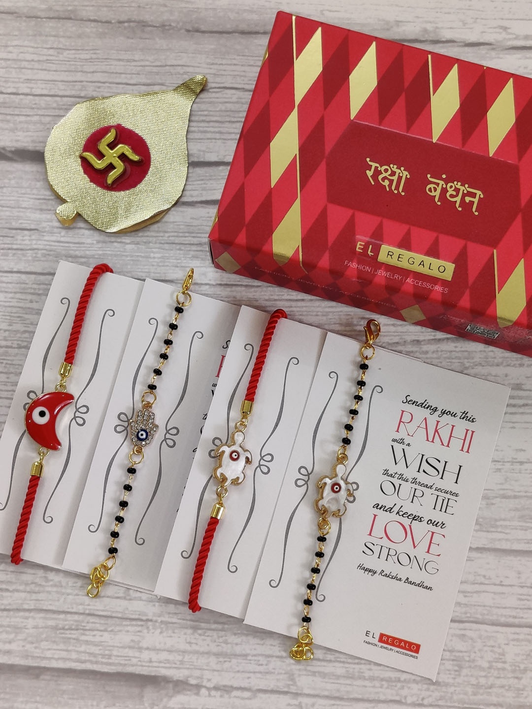 

EL REGALO Set Of 4 Red & Gold Coloured Evil Eye Wrap Around Rakhi With Roli Chawal & Raksha Bandhan Greeting Card