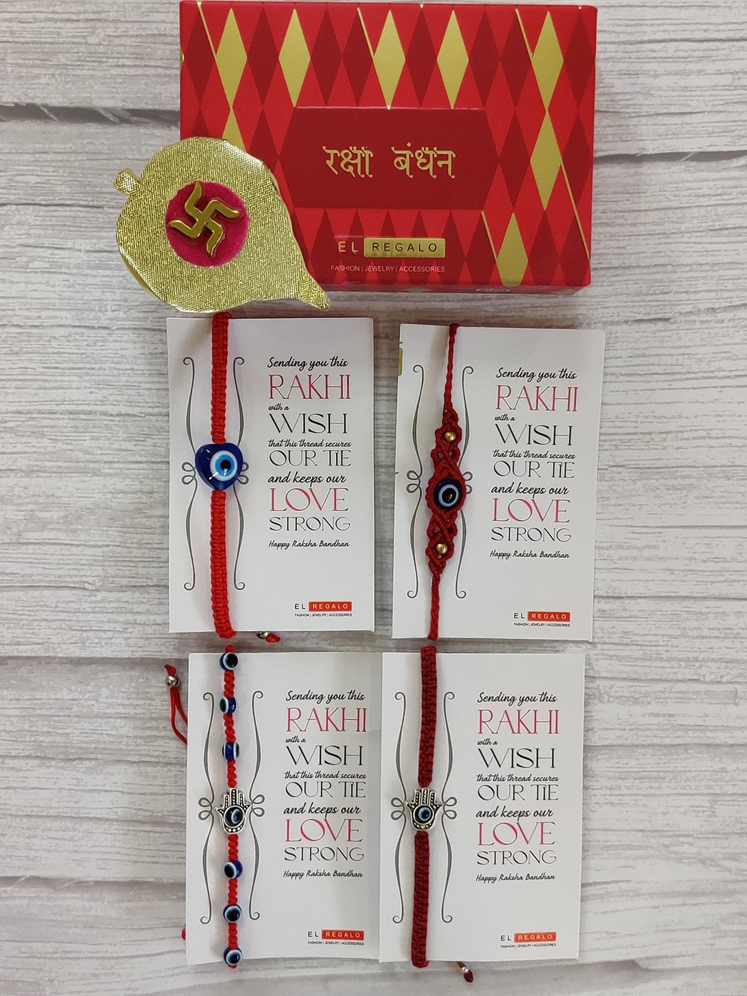 

EL REGALO Set Of 4 Red & Gold Coloured Evil Eye Wrap Around Rakhi With Roli Chawal & Raksha Bandhan Greeting Card