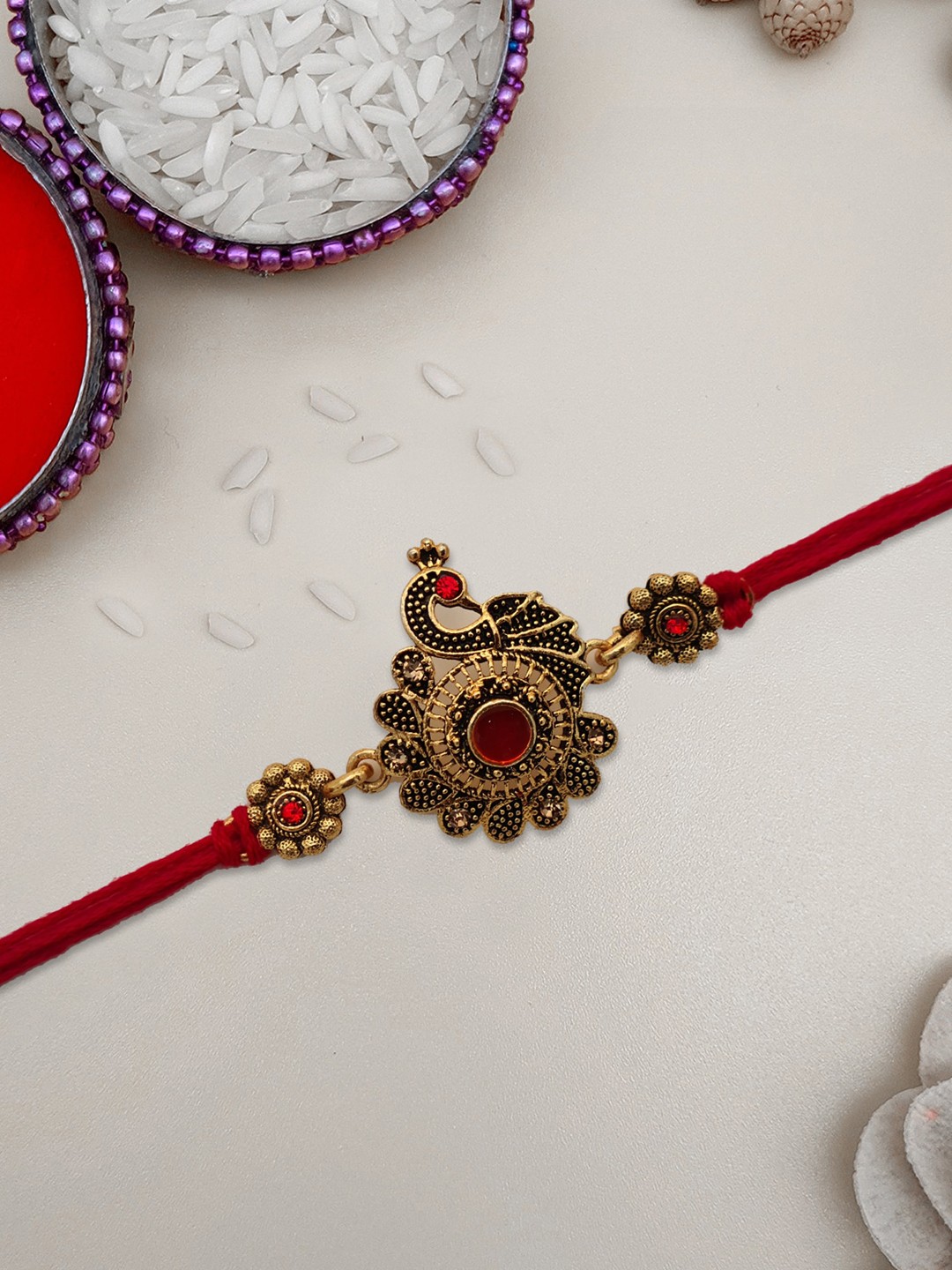 

STYBUZZ Gold-Toned & Red Peacock Design Rakhi With Greeting Card & Roli Chawal