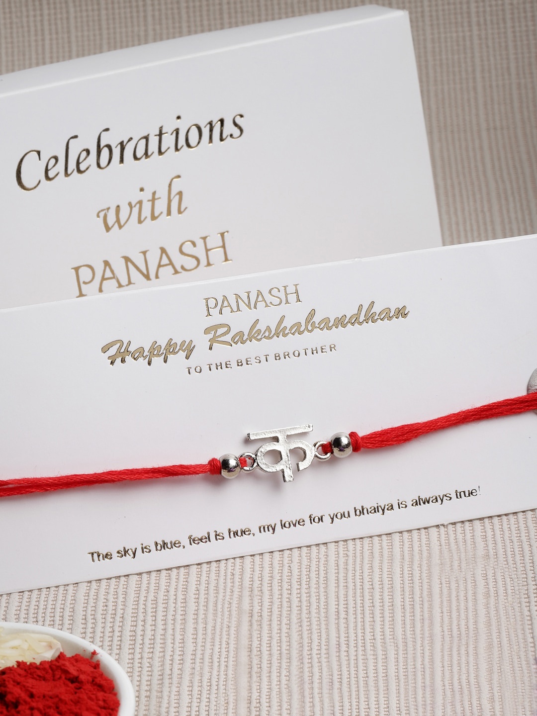 

PANASH Silver Toned Letter Handcrafted Convertible Pendant Rakhi with Roli Chawal