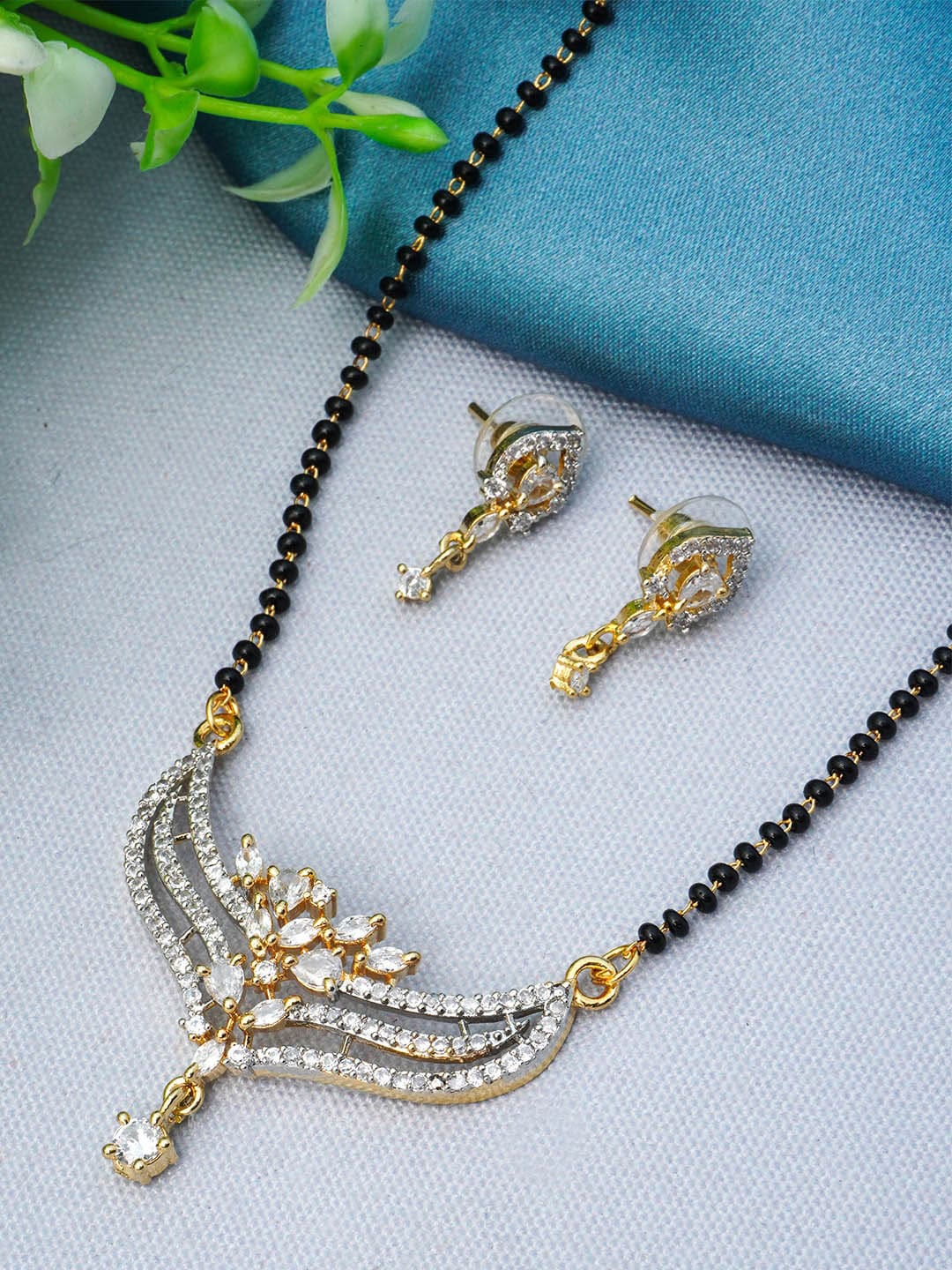 

Urmika Gold Plated Black Beaded White AD Studded Mangalsutra With Earring