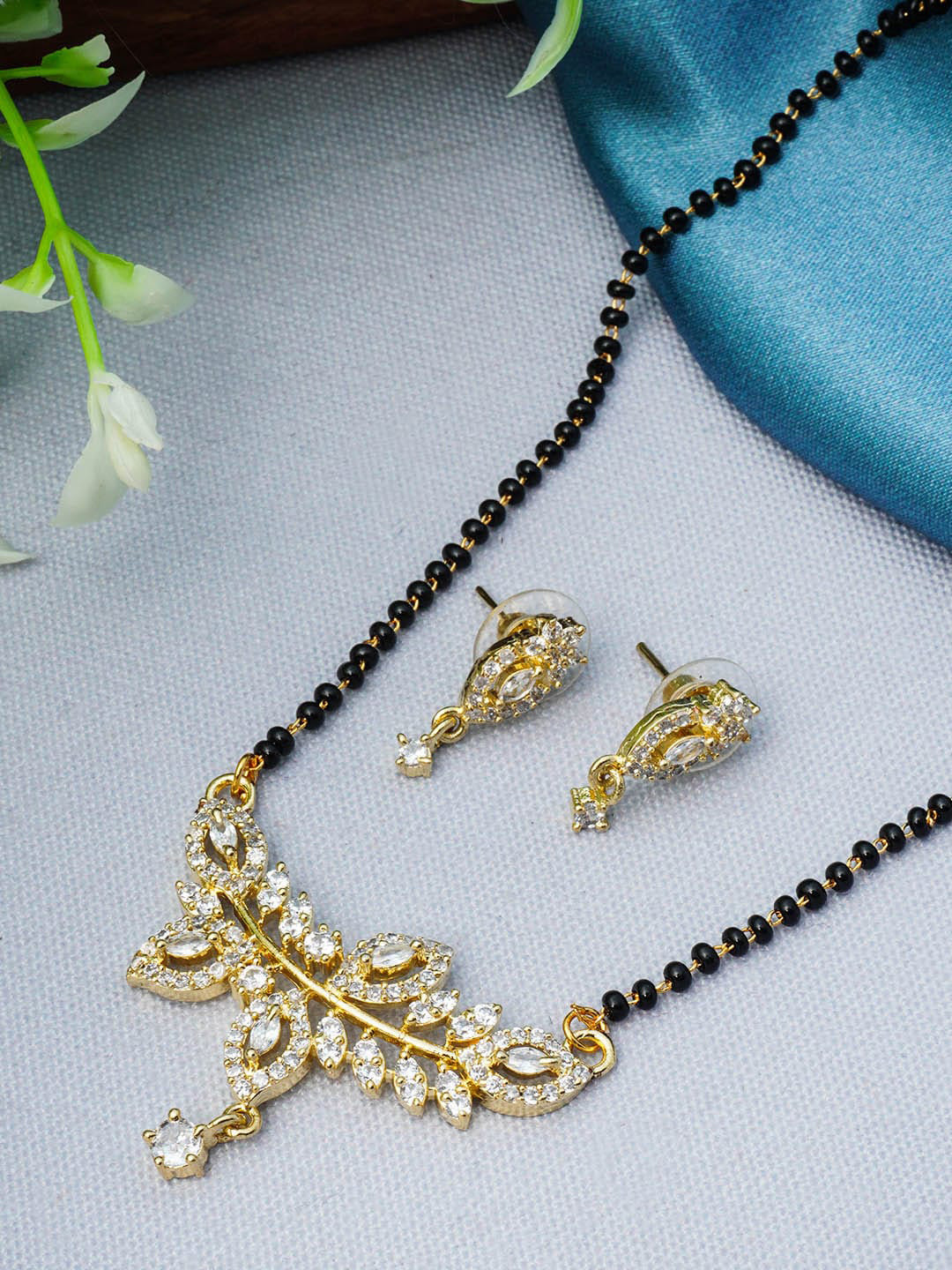 

Urmika Gold Plated Black Beaded White AD Studded Mangalsutra With Earring sets