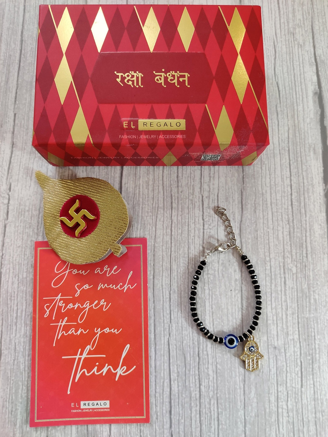 

EL REGALO Baby Gold Coloured Blue Evil Eye Rakhi With Roli Chawal & Rakhi Card