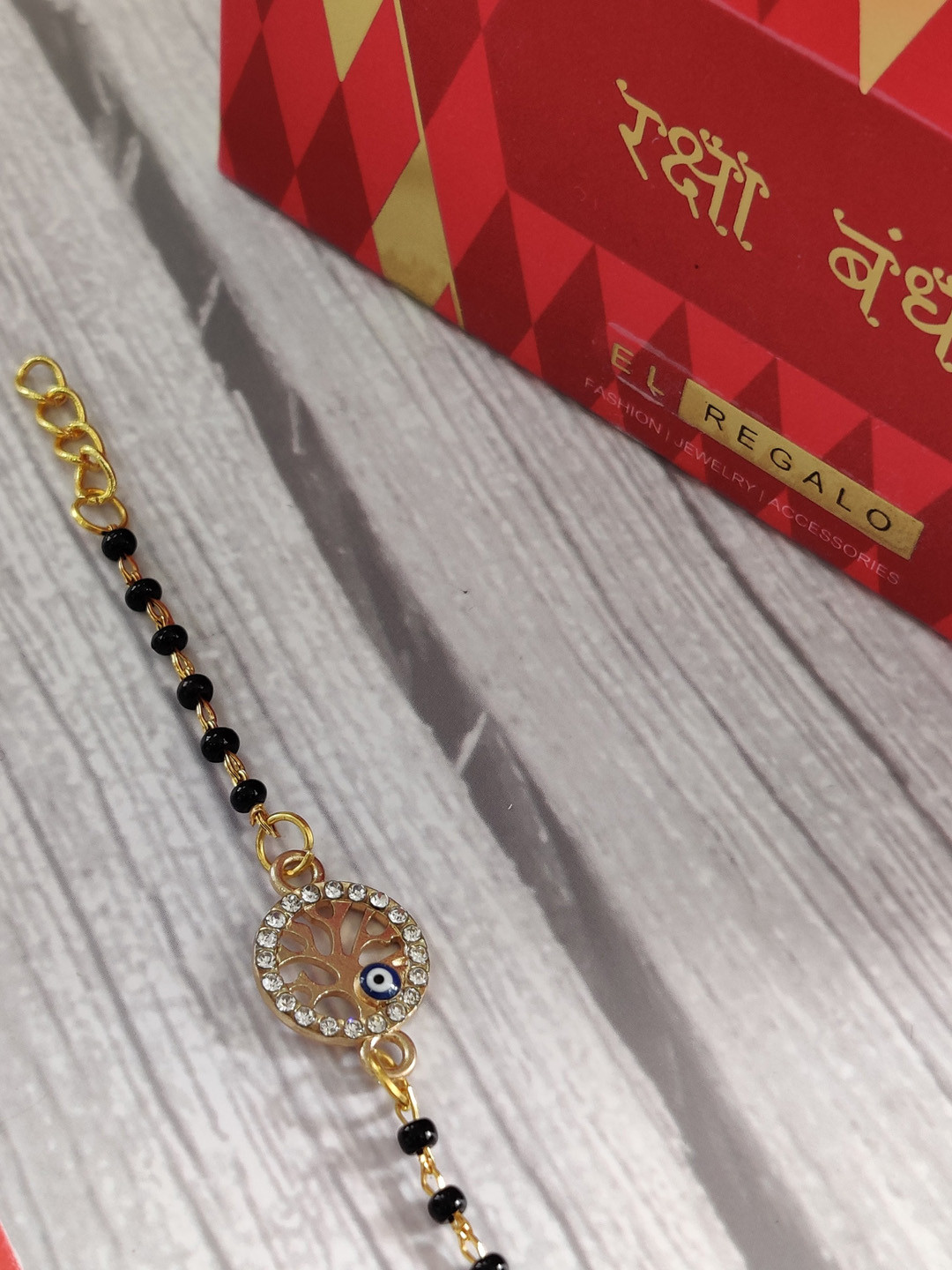 

EL REGALO Baby Gold Coloured Black Evil Eye Rakhi With Greeting Card