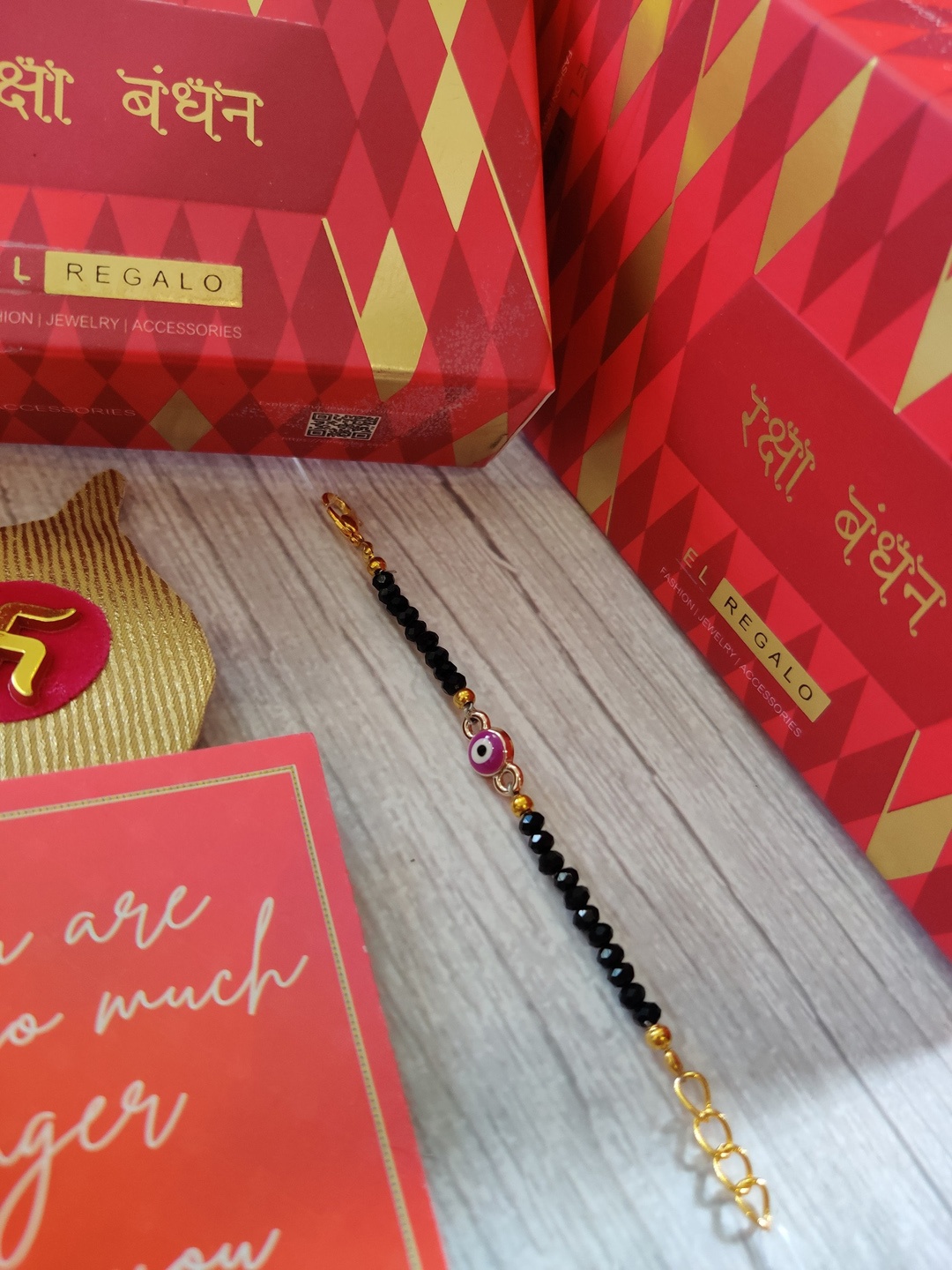

EL REGALO Baby Black Evil Eye Rakhi With Roli Chawal & Greeting Card, Magenta