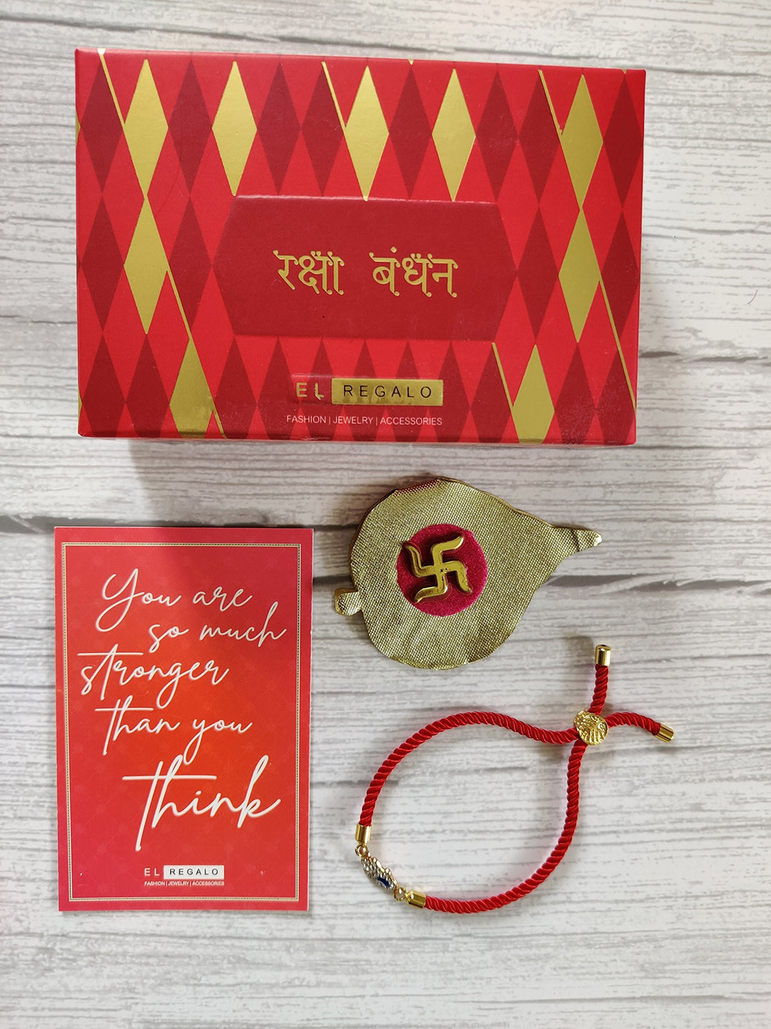 

EL REGALO Gold-Plated Red Coloured Evil Eye Rakhi With Greeting card & Roli Chawal