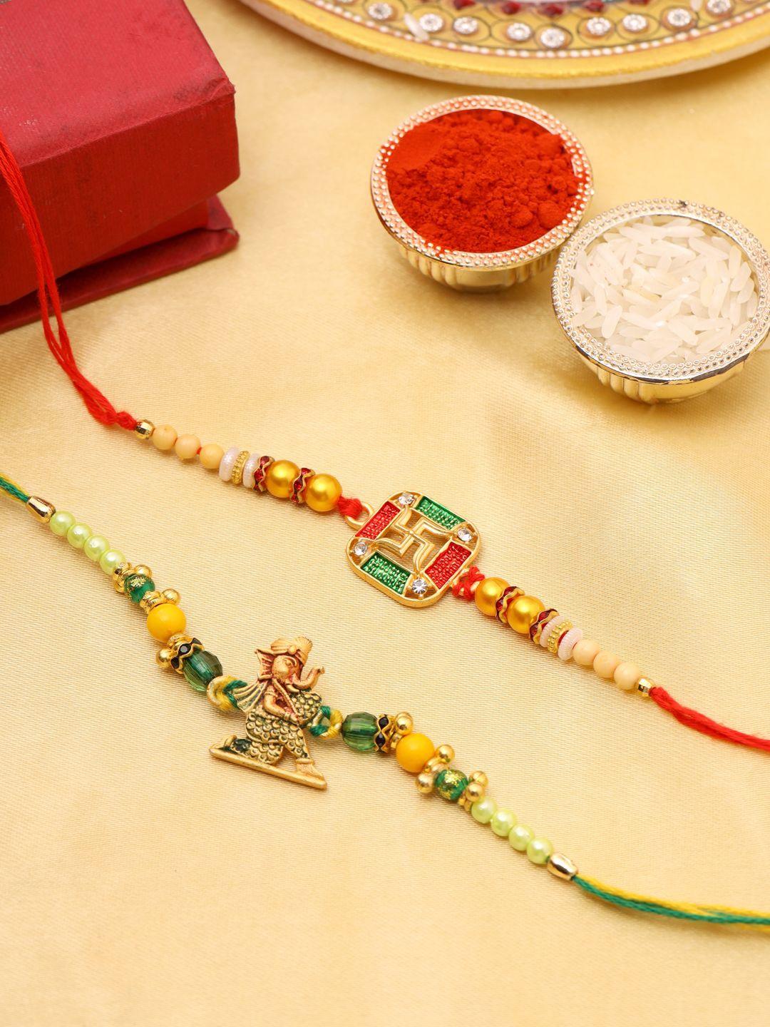 

Natures Buggy Set of 2 Religious Swastika & Lord Ganesha Beaded Thread Rakhis, Gold