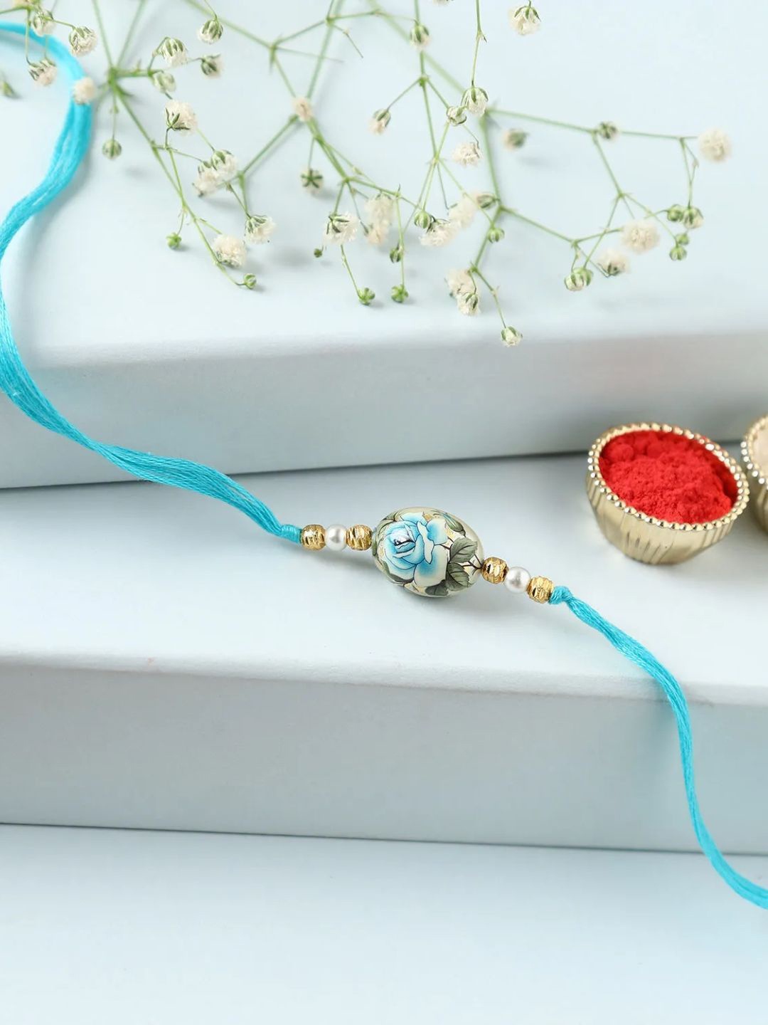 

fnp Azure Splendour Japanese Rose Rakhi Magical Evil Eye, Blue