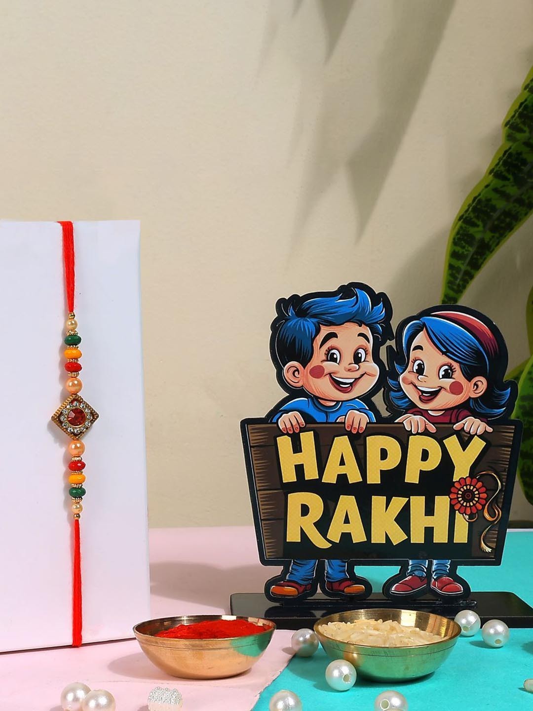 

Phirki Studio Set of 2 Beaded Thread Rakhi With Brosis Table Stand & Roli Chawal, Red