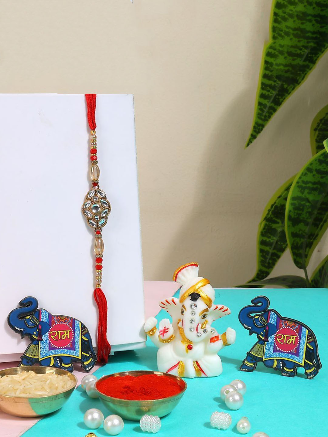 

Phirki Studio Set of 2 Stone Studded Rakhi With God Figure Table stand & Roli Chawal, Red