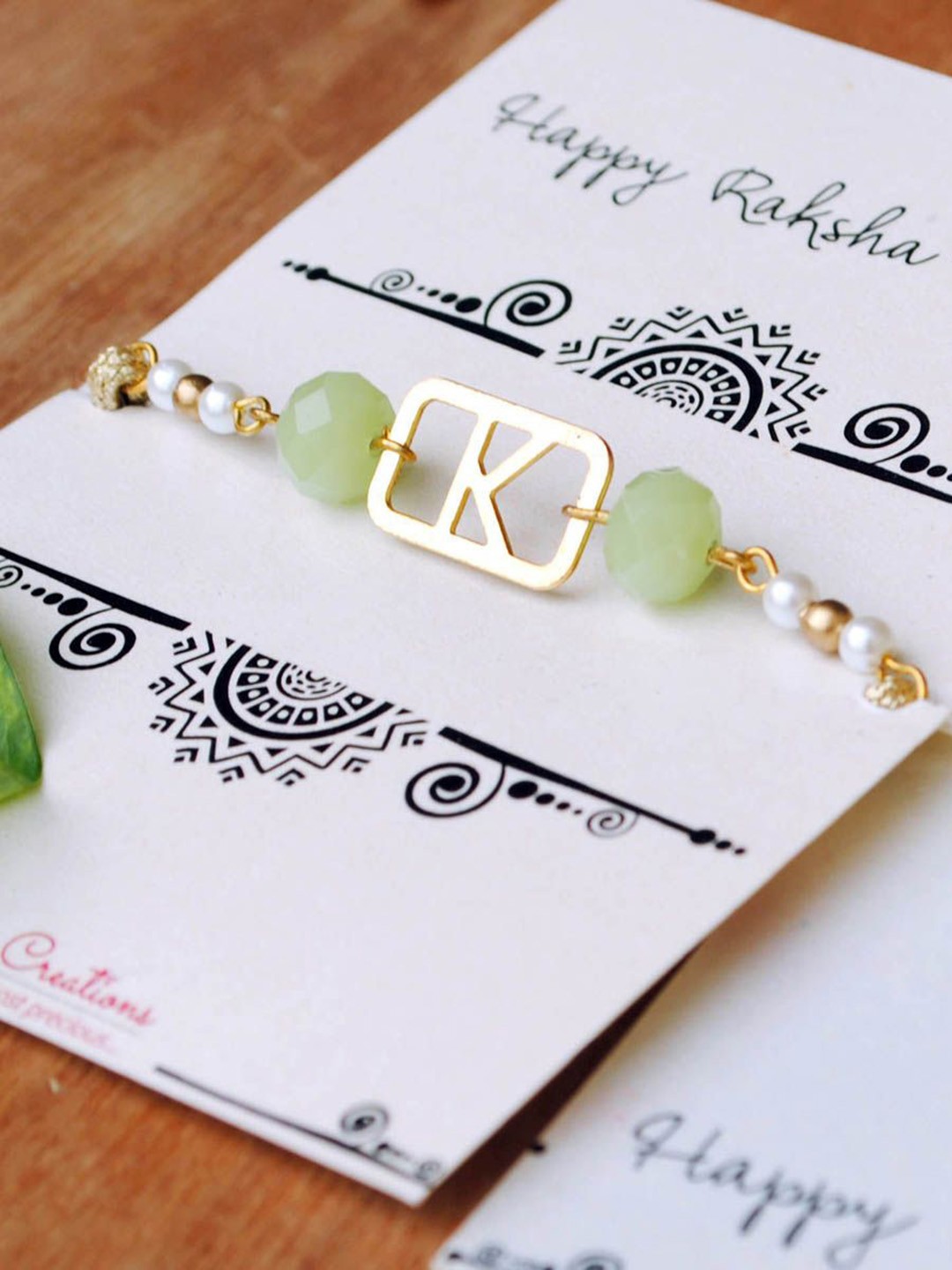 

BeAbhika S Initial Beaded Thread Rakhi with Roli Chawal Capsules, Green