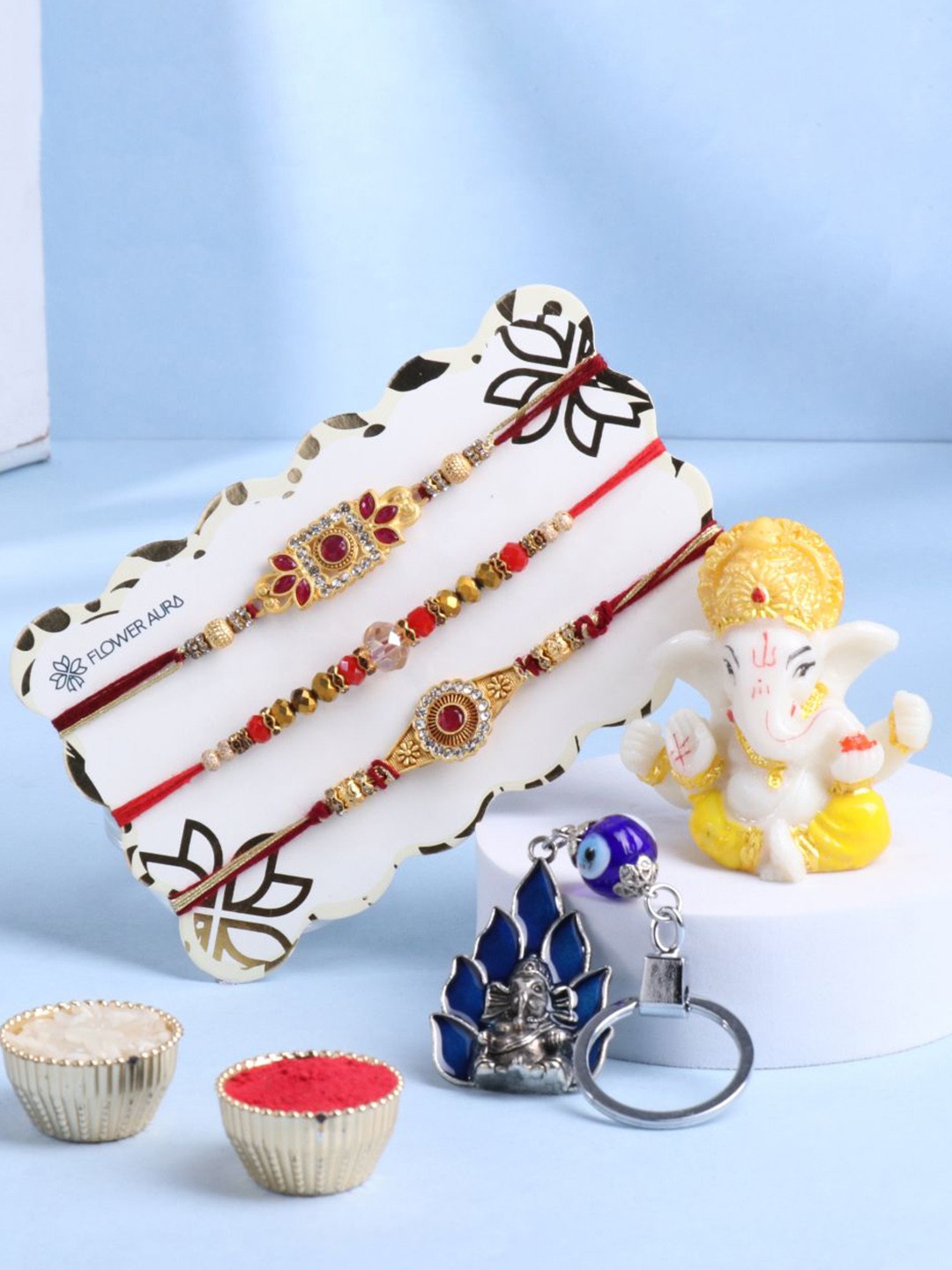 

Floweraura Set Of 5 Rakhis With Lord Ganesha Idol, Keychain & Roli Cawal Gift Set, Red
