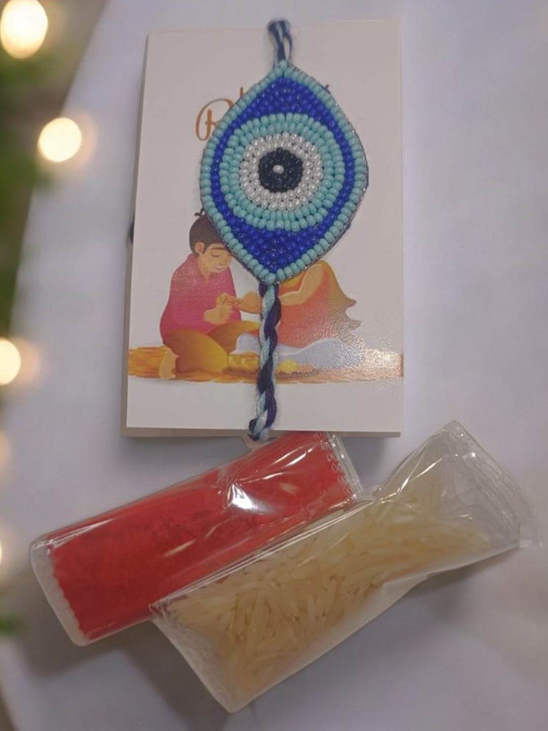 

PRIAANSHA CREATIONS Evil Eye Embellished Thread Rakhi With Roli Chawal & Greeting Card, Blue