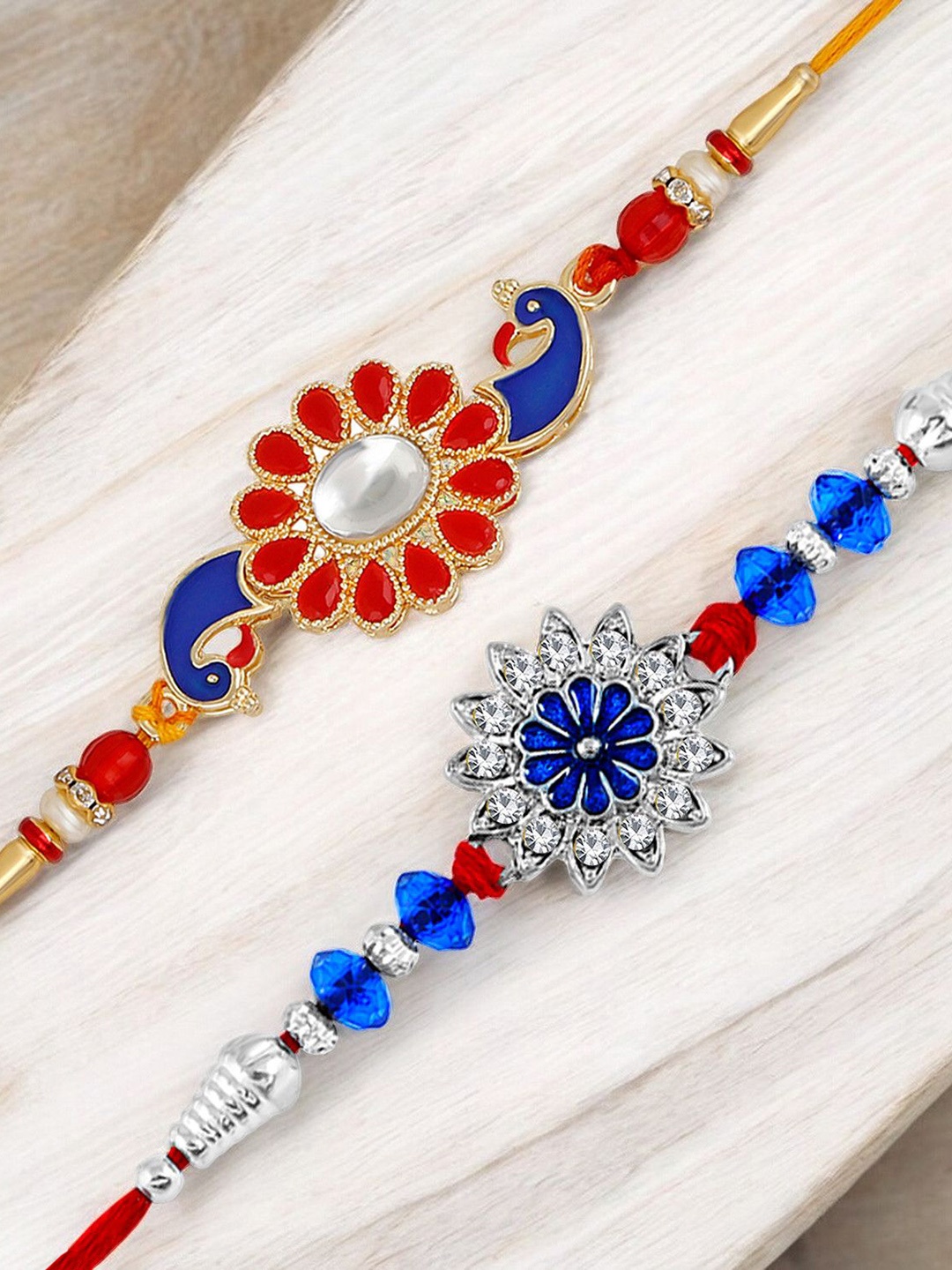 

Okos Set Of 2 Gold and Rhodium Plated Meenakari Peacock and Flower Shape Thread Rakhis, Blue