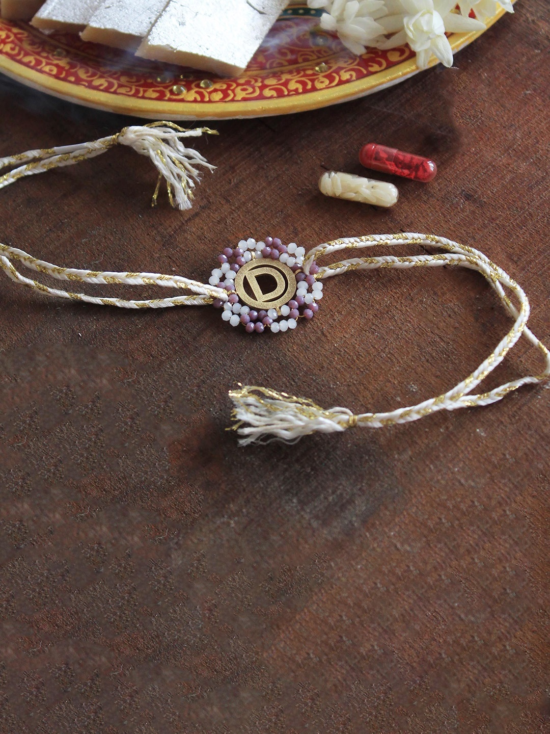 

BeAbhika "M" Initial Beaded Thread Rakhi with Roli Chawal Capsules, White