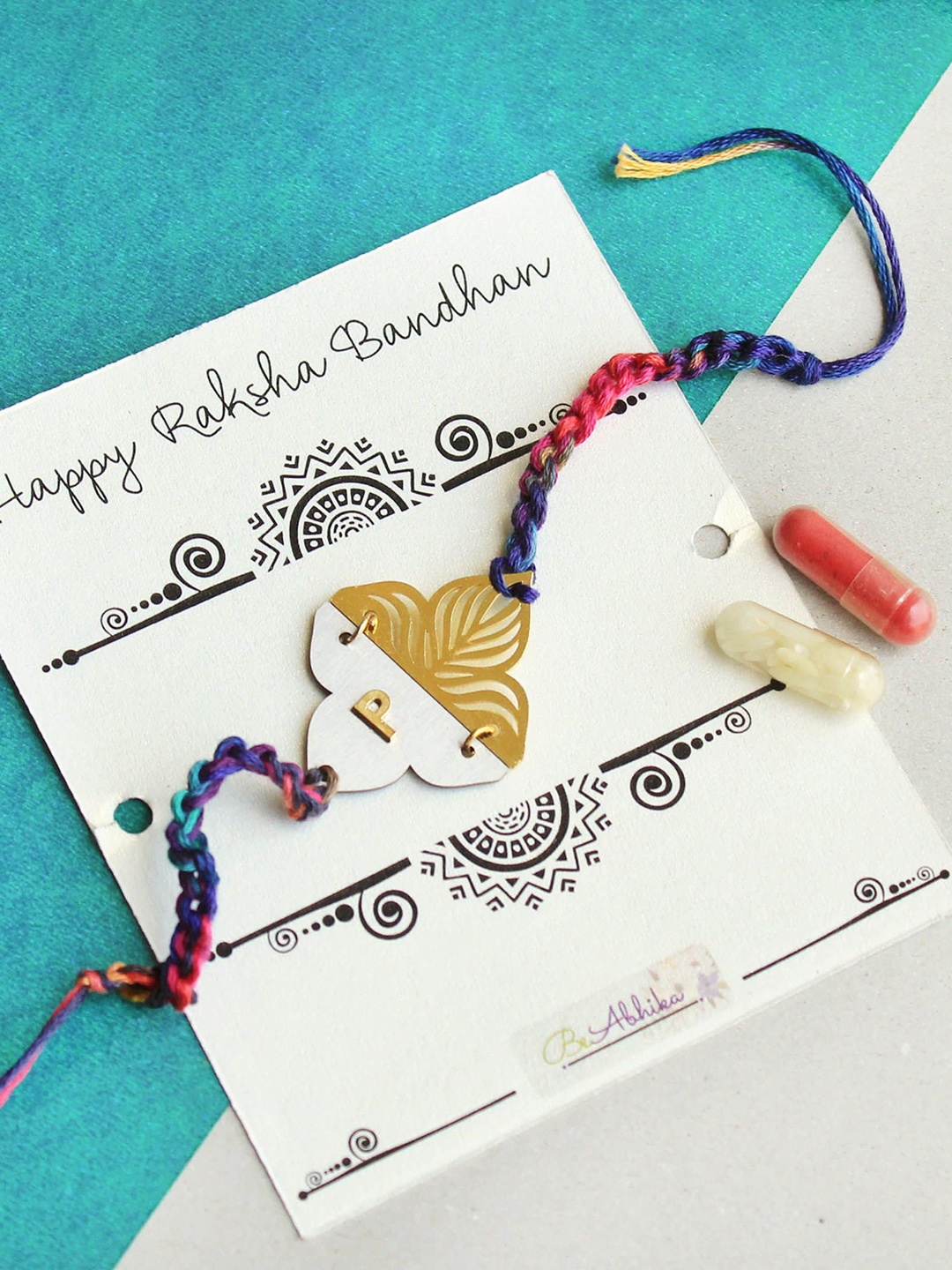 

BeAbhika R Initial Personalised Floral Plate Thread Rakhi with Roli Chawal Capsules, Red