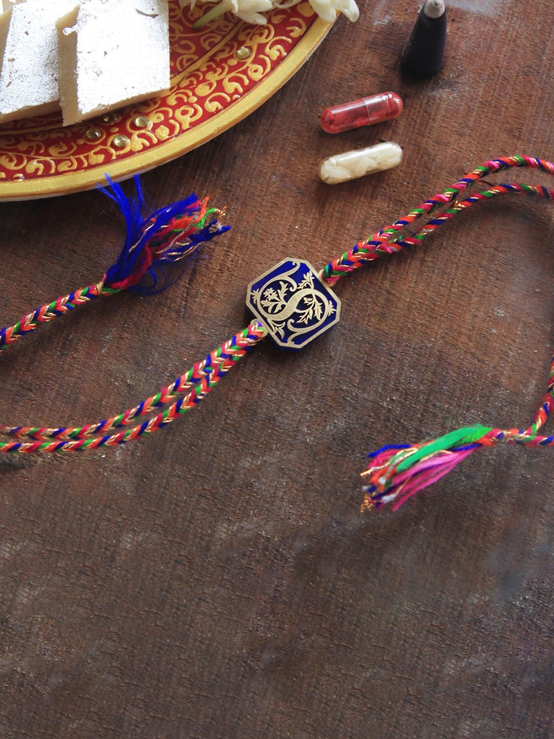 

BeAbhika B Initial Floral Thread Rakhi with Roli Chawal Capsules, Blue