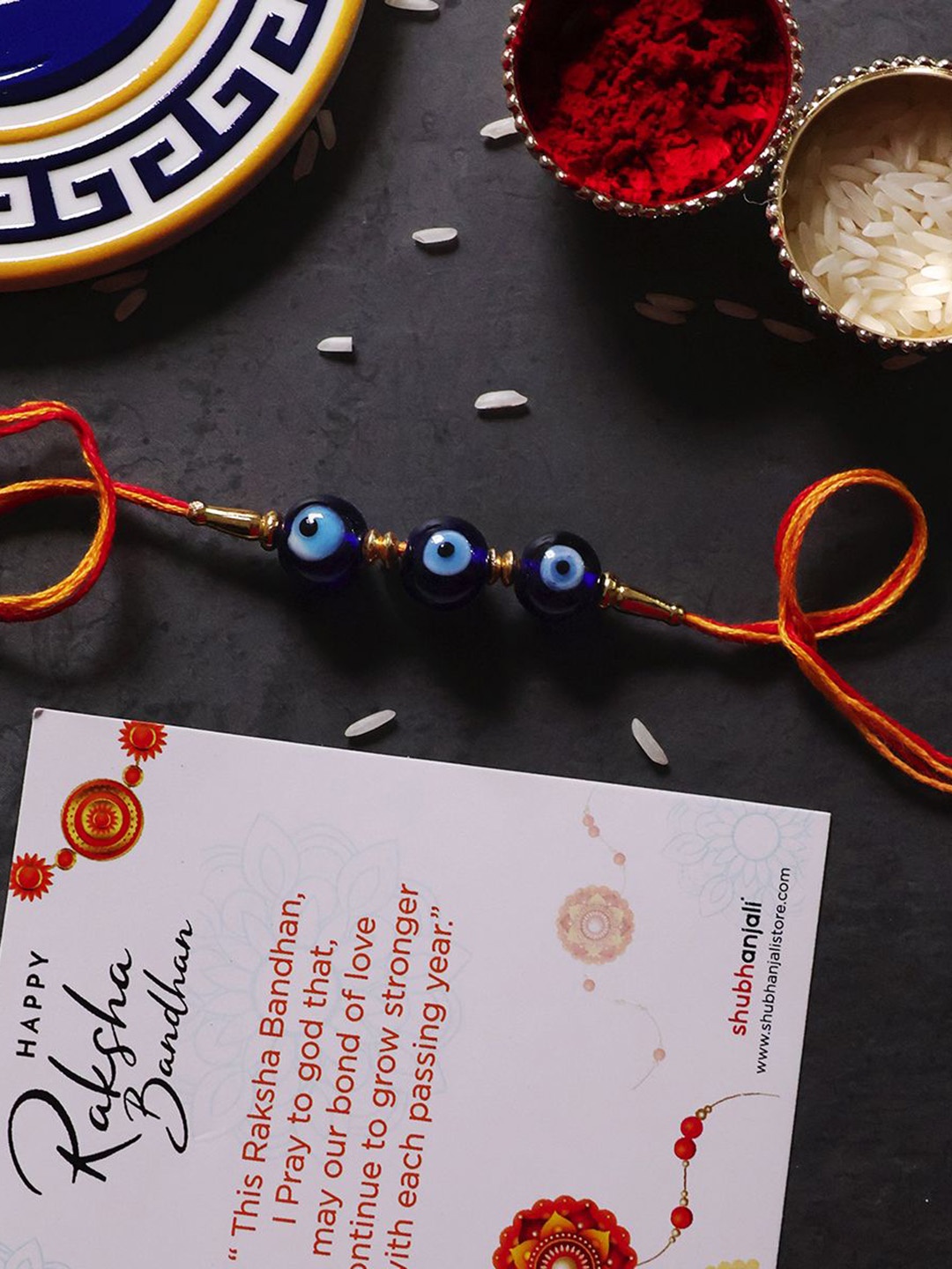 

Shubhanjali Set Of 2 Evil Eye Beads Thread Rakhis With Roli Chawal & Greeting Card, Orange