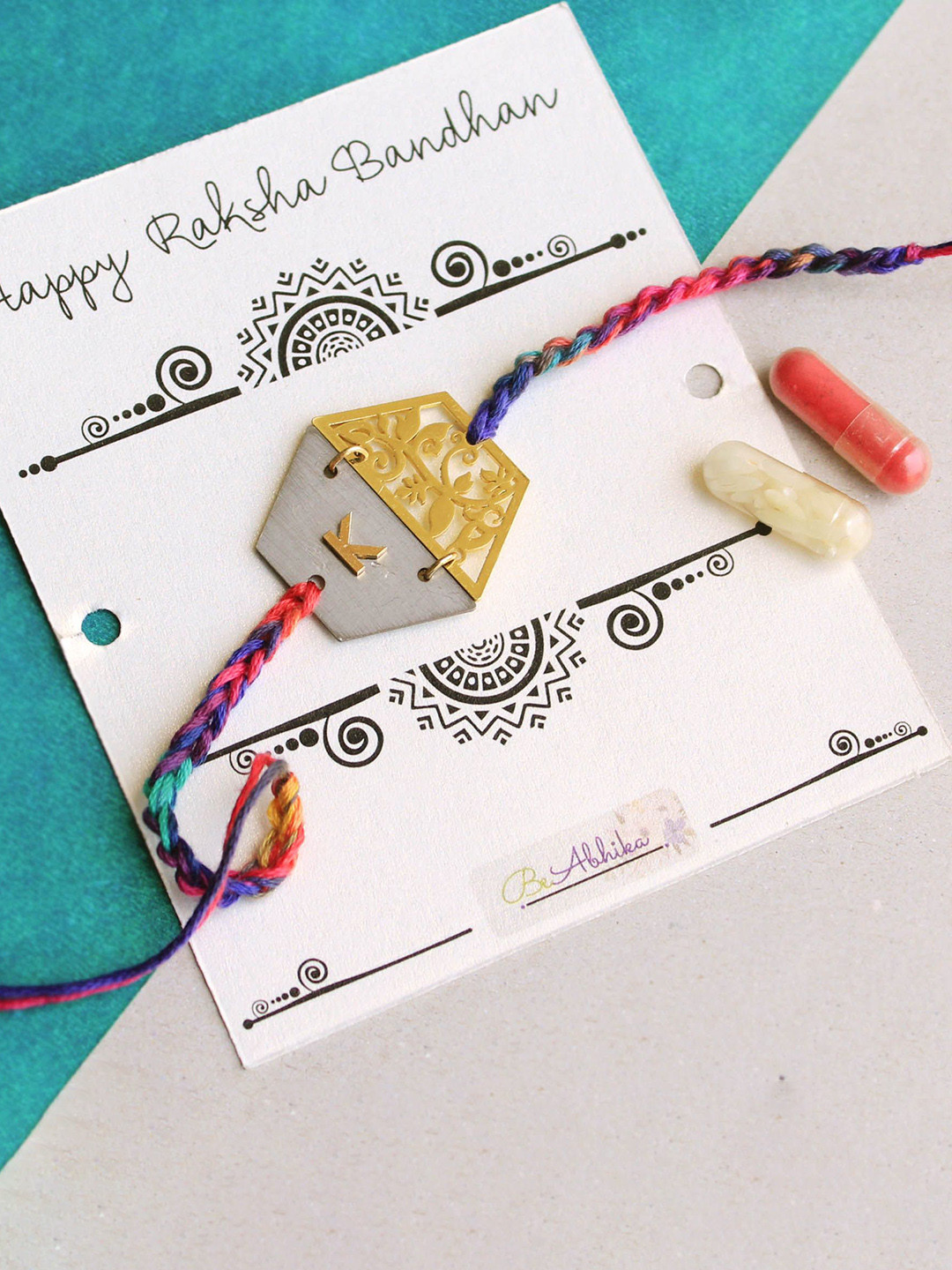 

BeAbhika U Initial Personalised Floral Hexagon Plate Rakhi with Roli Chawal Capsules, Red