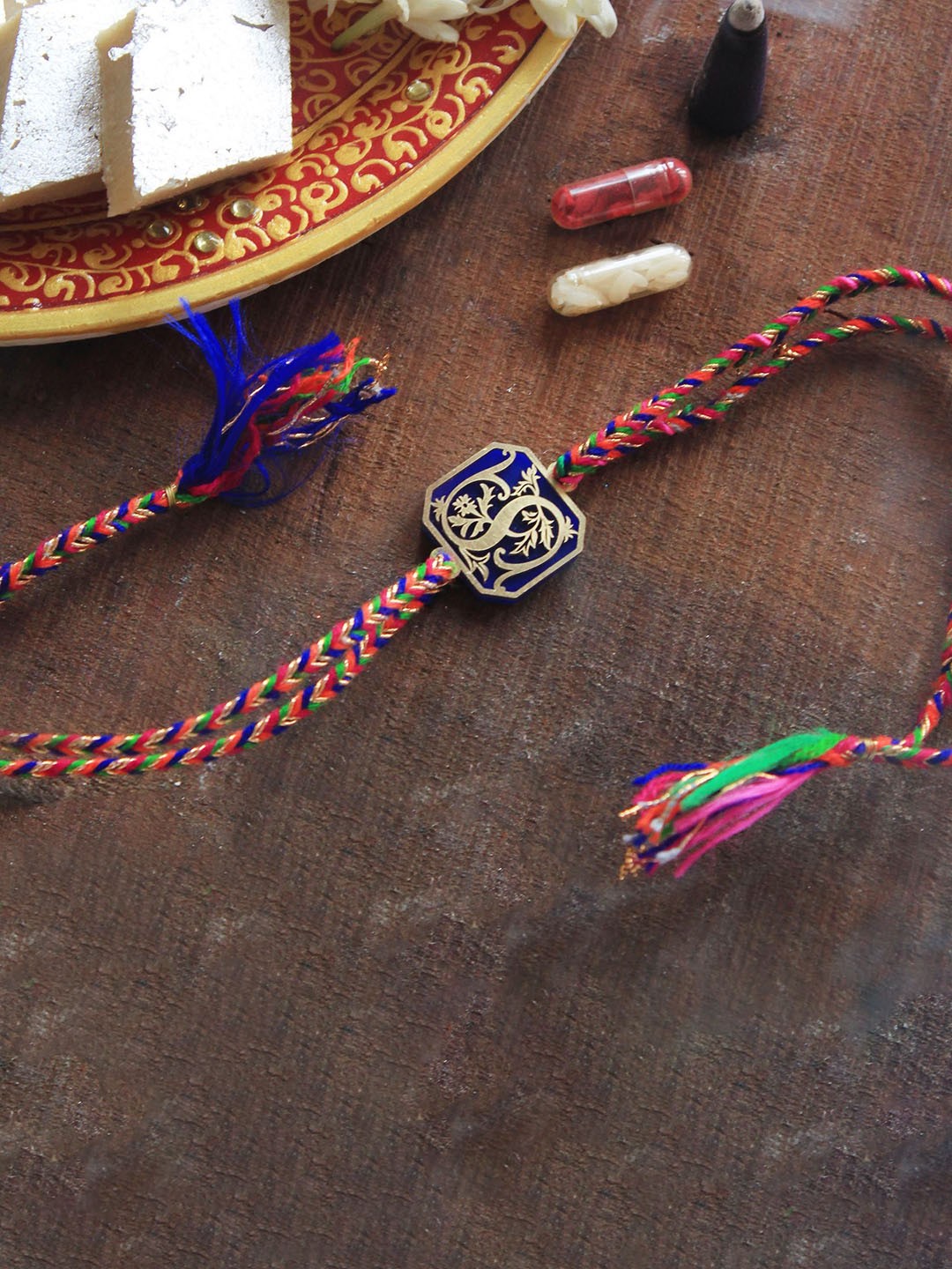 

BeAbhika C Initial Floral Thread Rakhi With Roli & Chawal Capsules, Blue