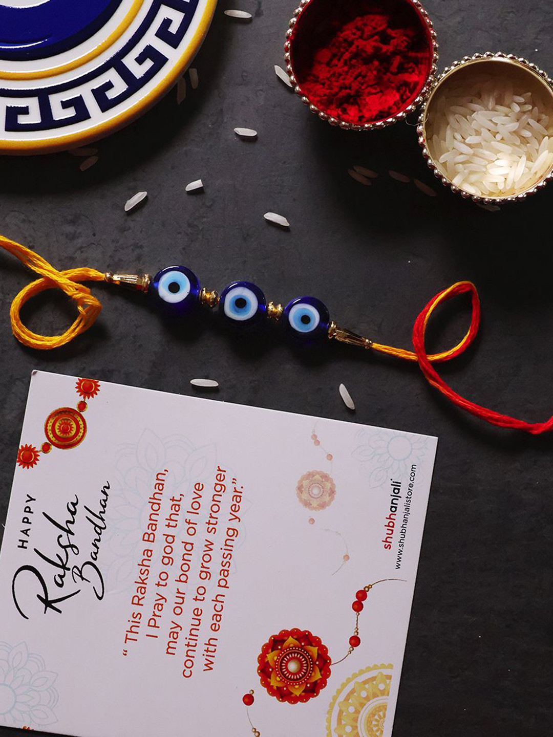 

Shubhanjali Set Of 2 Evil Eye Beads Thread Rakhis With Roli Chawal & Greeting Card, Blue