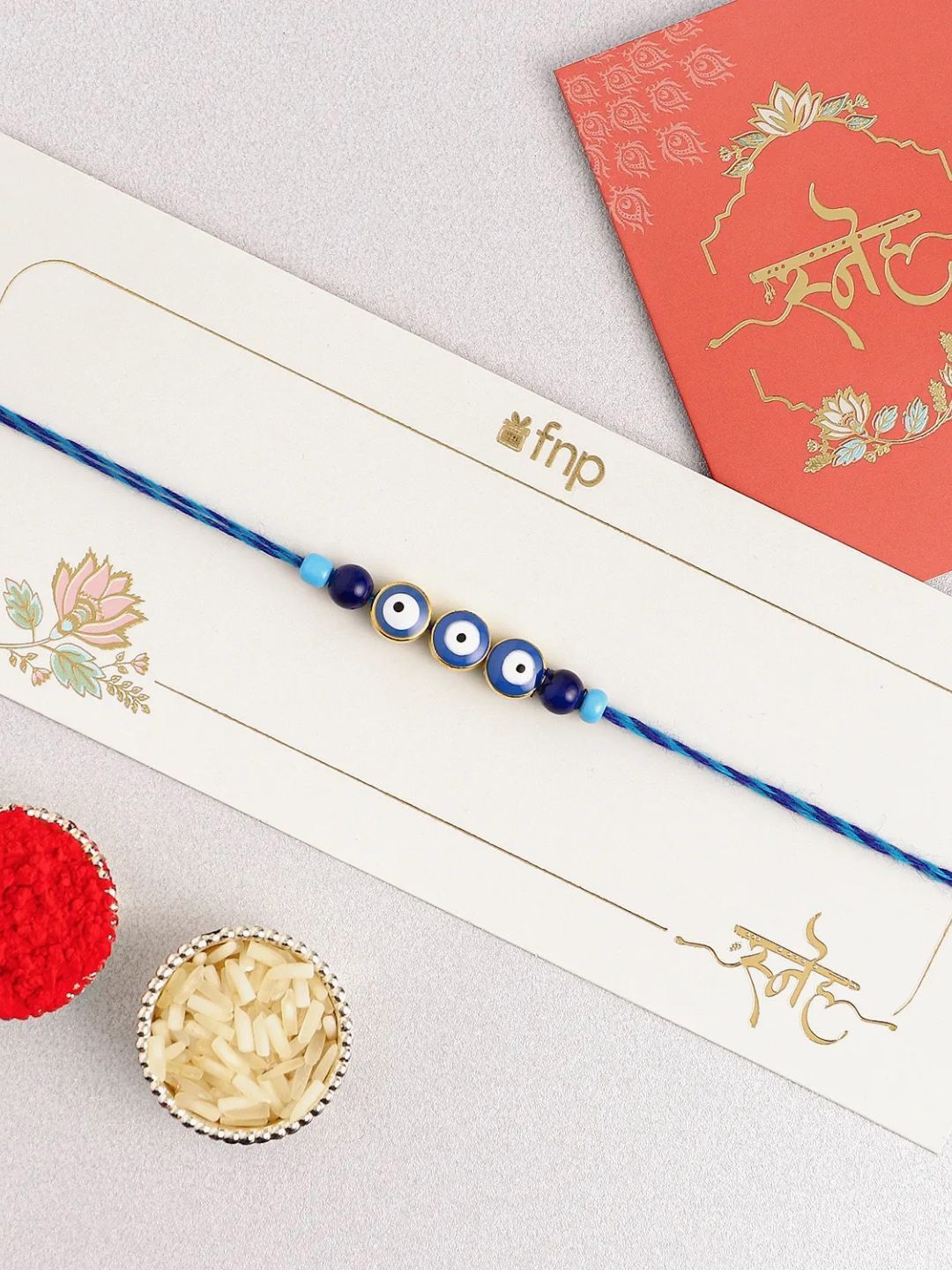 

fnp Evil-Eye Rakhi & Butterscotch Cake With Roli Chawal Gift Set, Navy blue