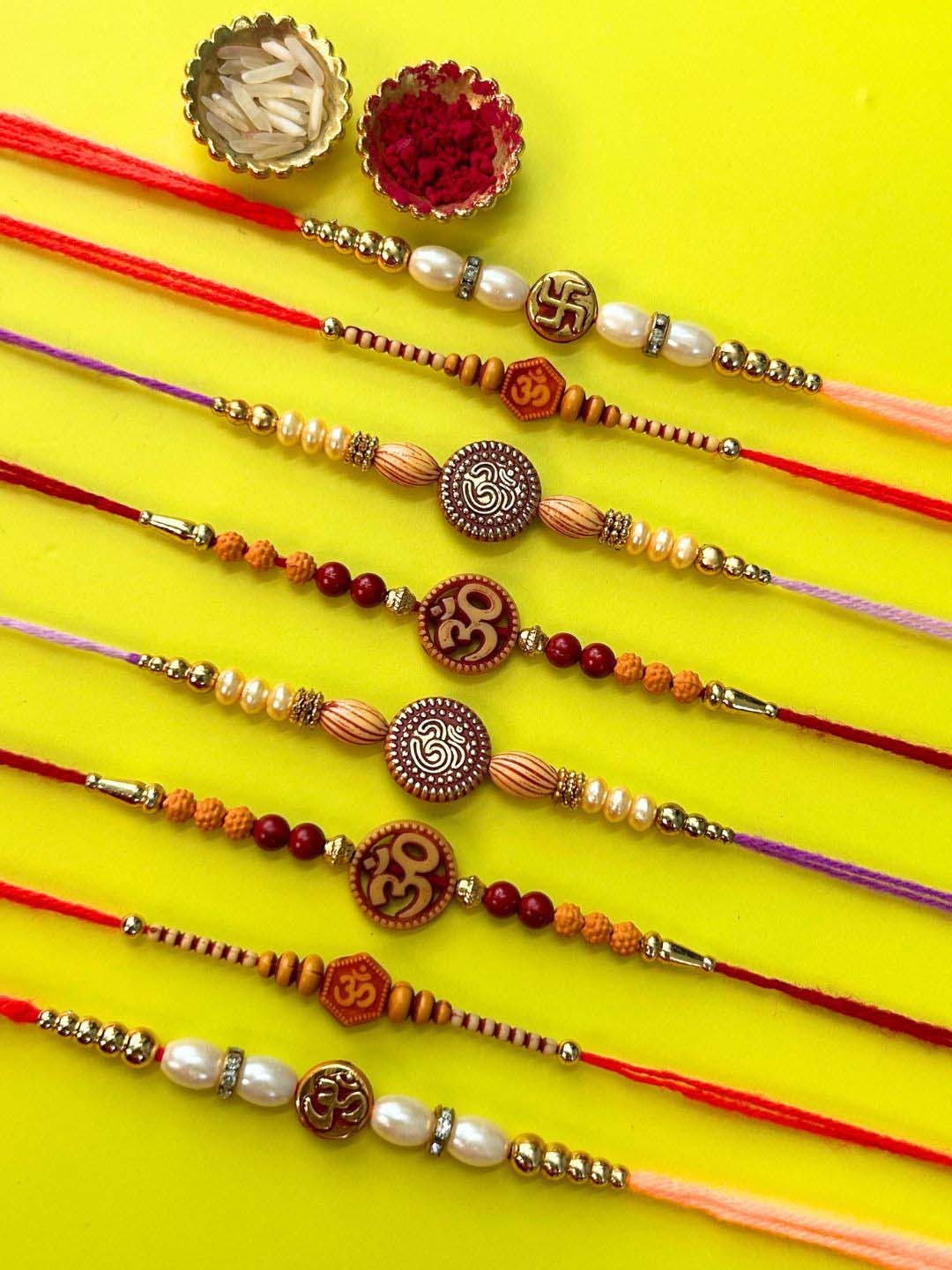 

LAIDA Set Of 8 Om And Swastik Gemstone Studded & Beaded Thread Rakhis With Roli Chawal, Red