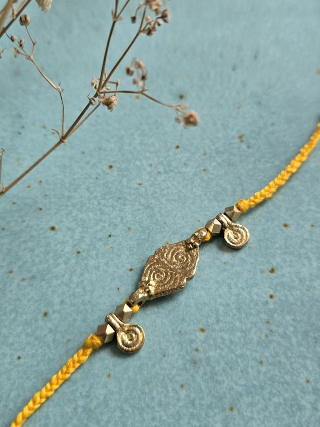 

Studio Anviksha Brass Charm Cotton Thread Rakhi, Gold
