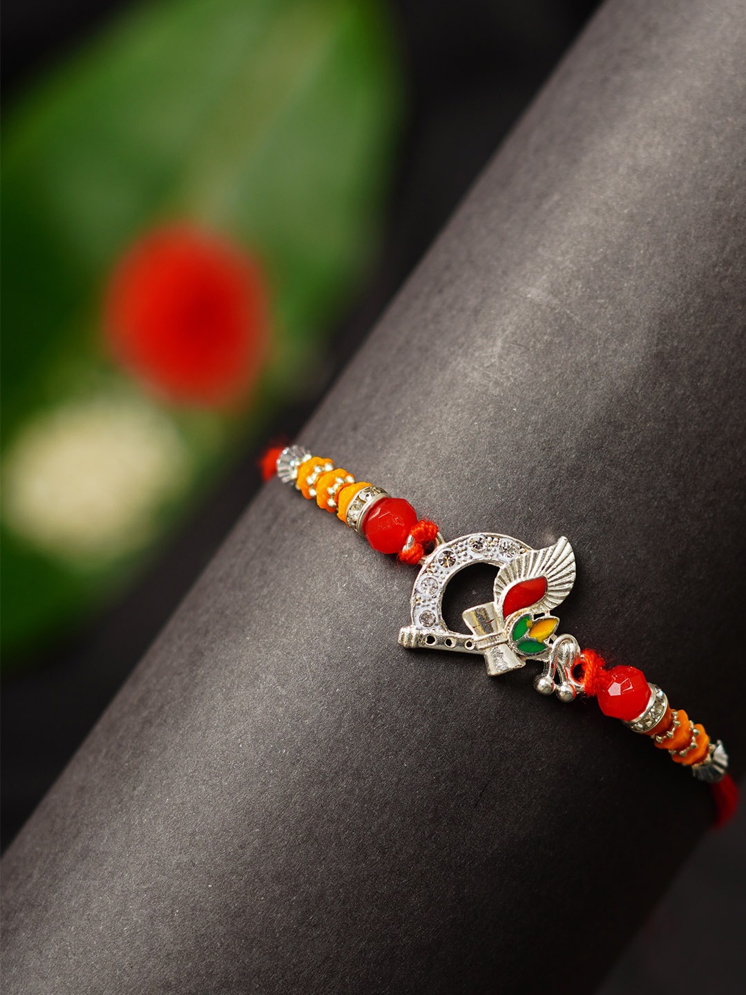 

Urmika Bansuri Damroo Religious Rakhi With Roli Chawal, Red