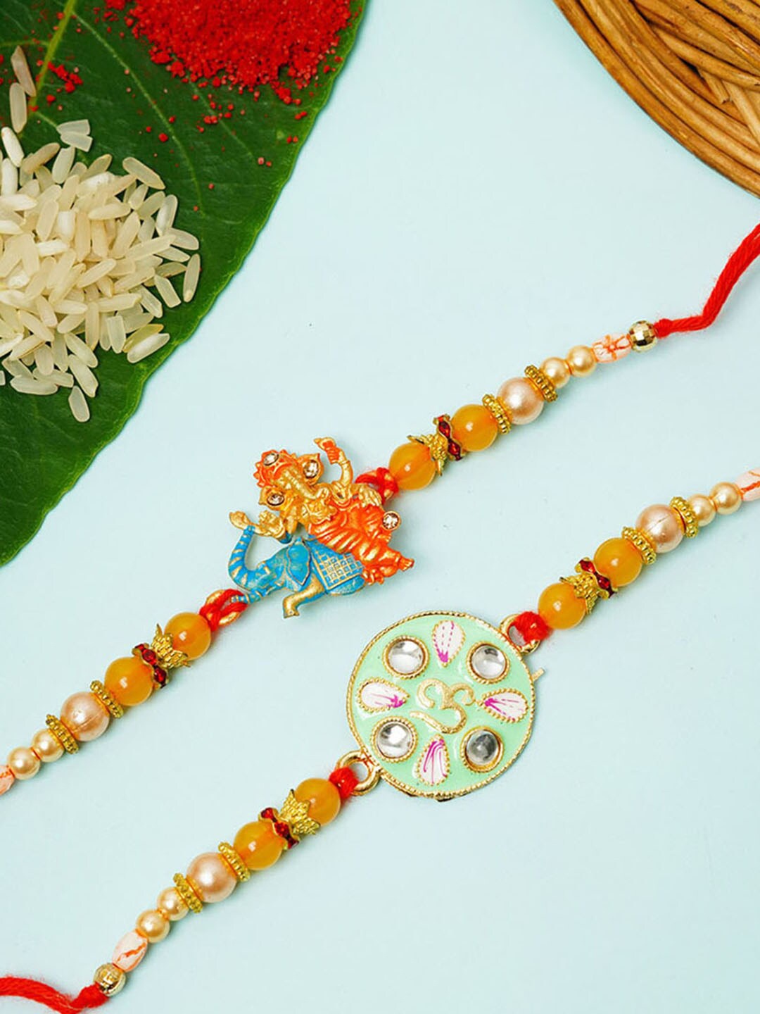 

Urmika Set Of 2 Shri Ganesh & Crystal Meenakari Thread Rakhi, Green