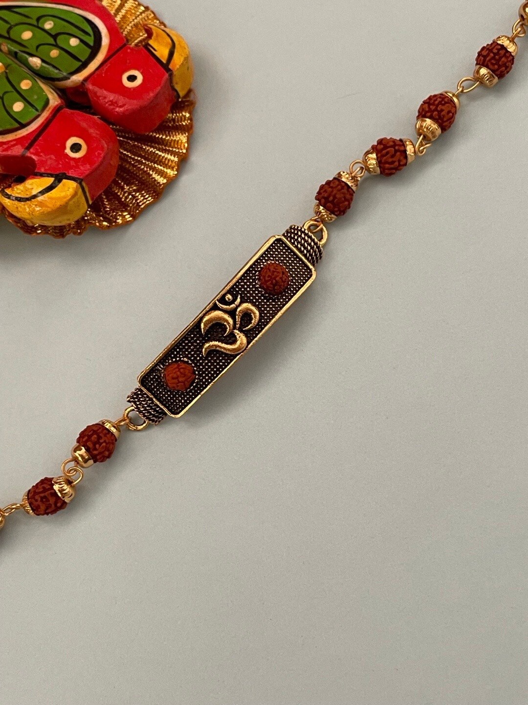 

Digital Dress Room Gold-Plated Om With Small Rudraksha Charm Rakhi