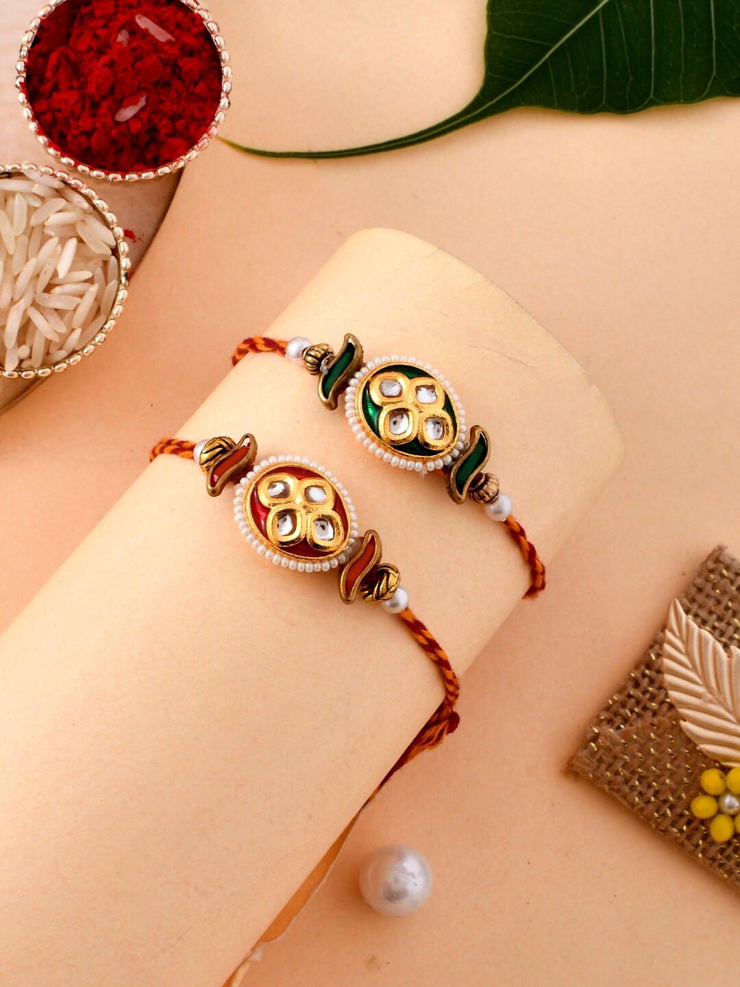 

Aapno Rajasthan Set Of 2 Pearl and Kundan Couture Rakhi With Roli Rice & Greeting Card, Red