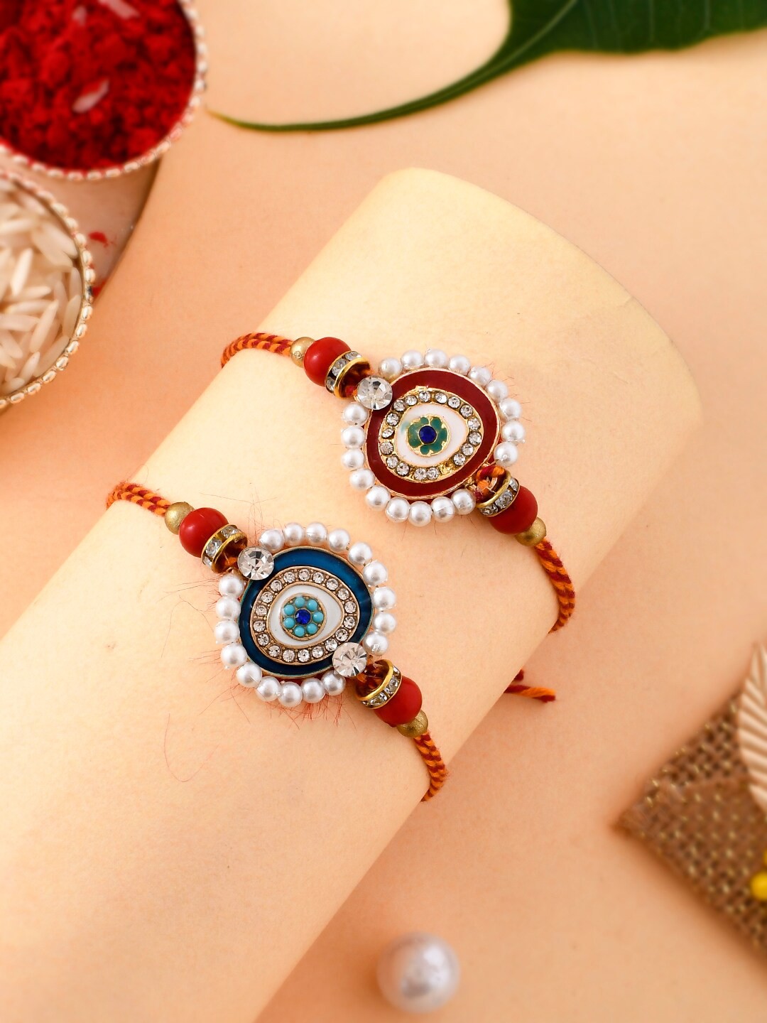 

Aapno Rajasthan Unisex Set Of 2 Pearl & Kundan Rakhi With Roli, Rice & Greeting Card, Red