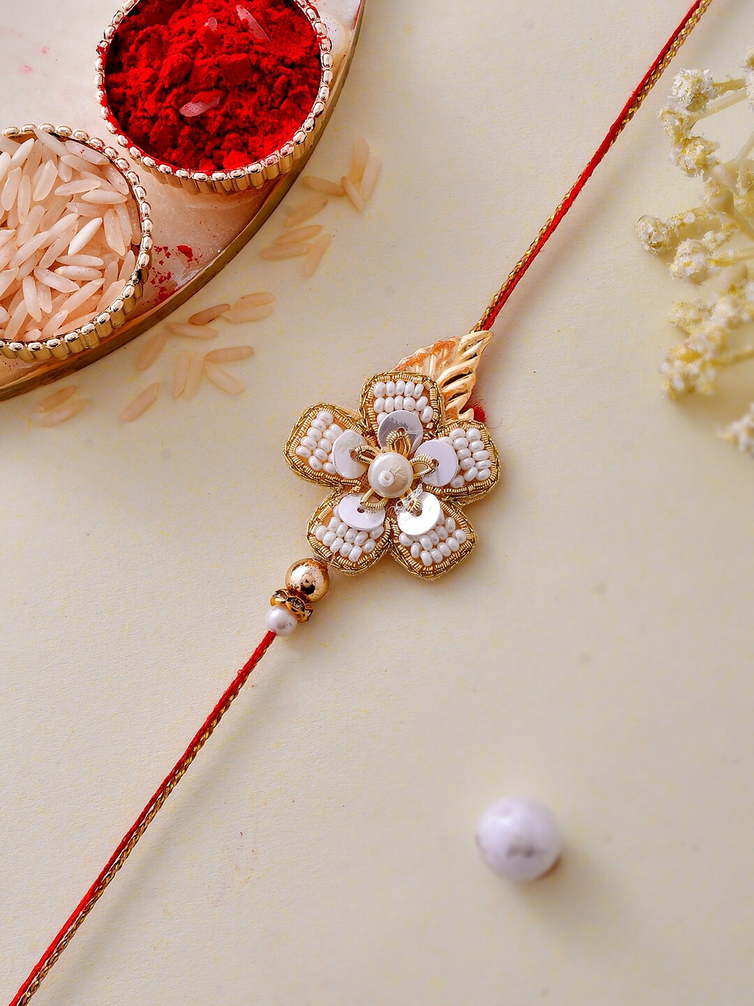 

Aapno Rajasthan Gold-Plated Pearl & Sequin Embellished Dazzling Floral Rakhi
