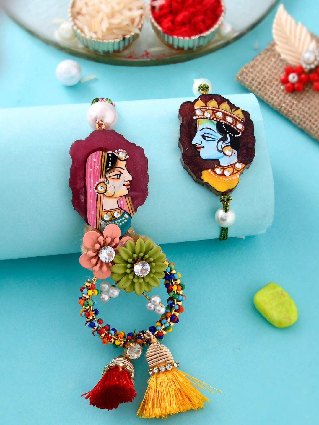 

Aapno Rajasthan Unisex Set Of 2 Stone Studded & Beaded Radha-Krishna Bhaiya Bhabhi Rakhis, Red