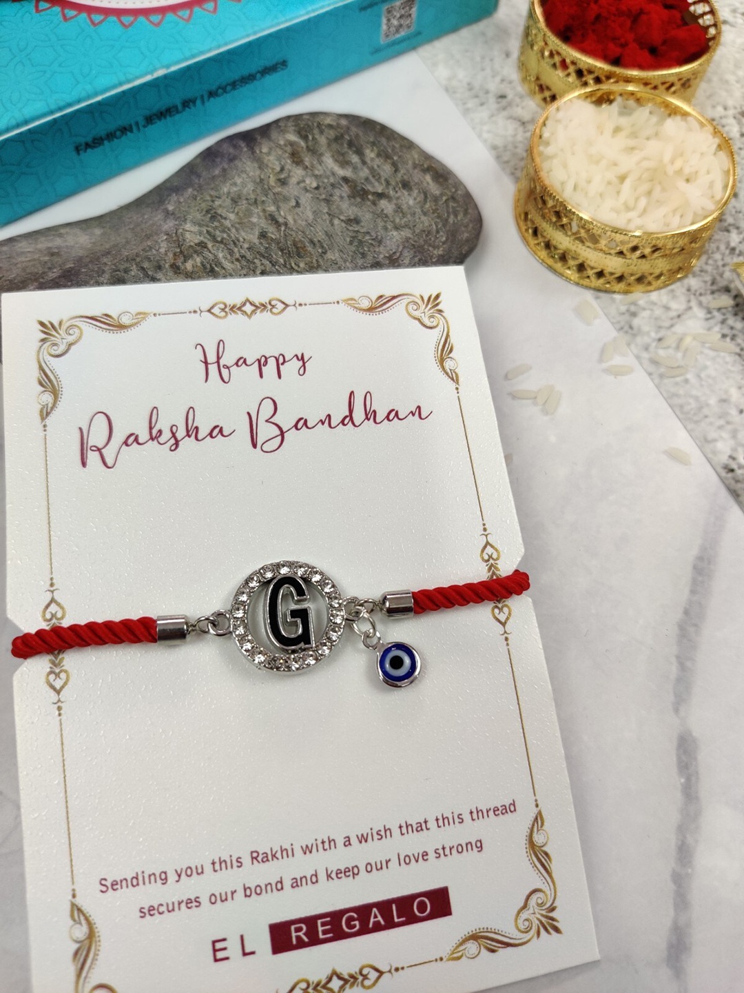 

EL REGALO G Name Initial Evil Eye Rakhi With Roli Chawal, Red
