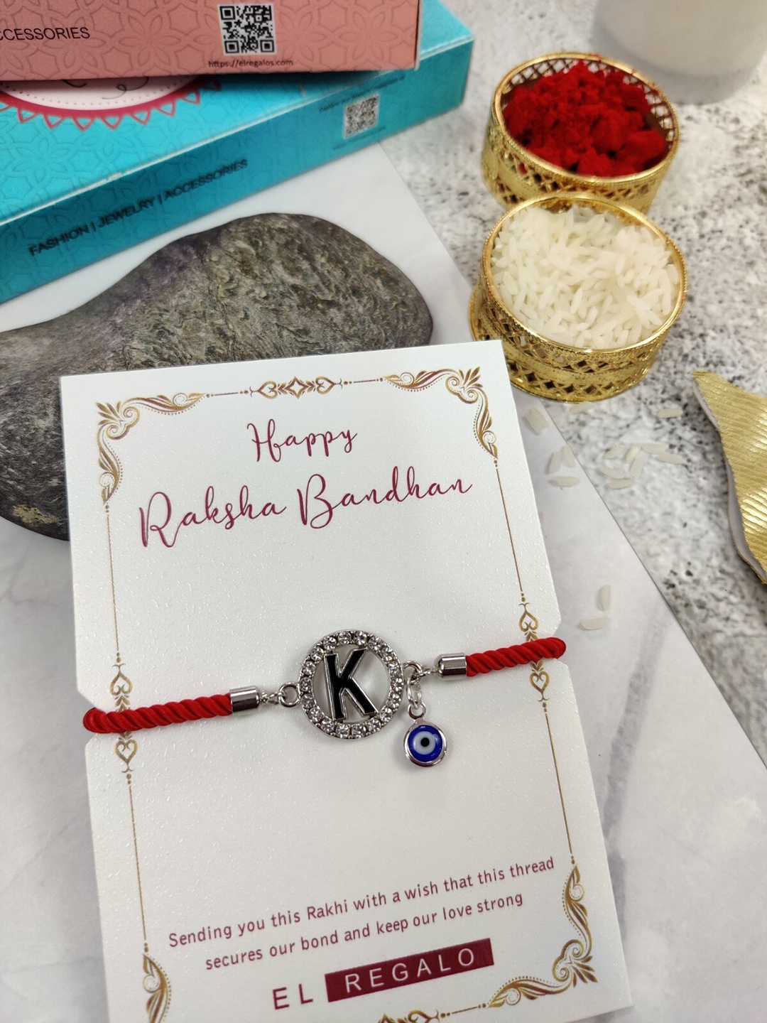 

EL REGALO K Name Initial Evil Eye Rakhi With Roli Chawal, Red
