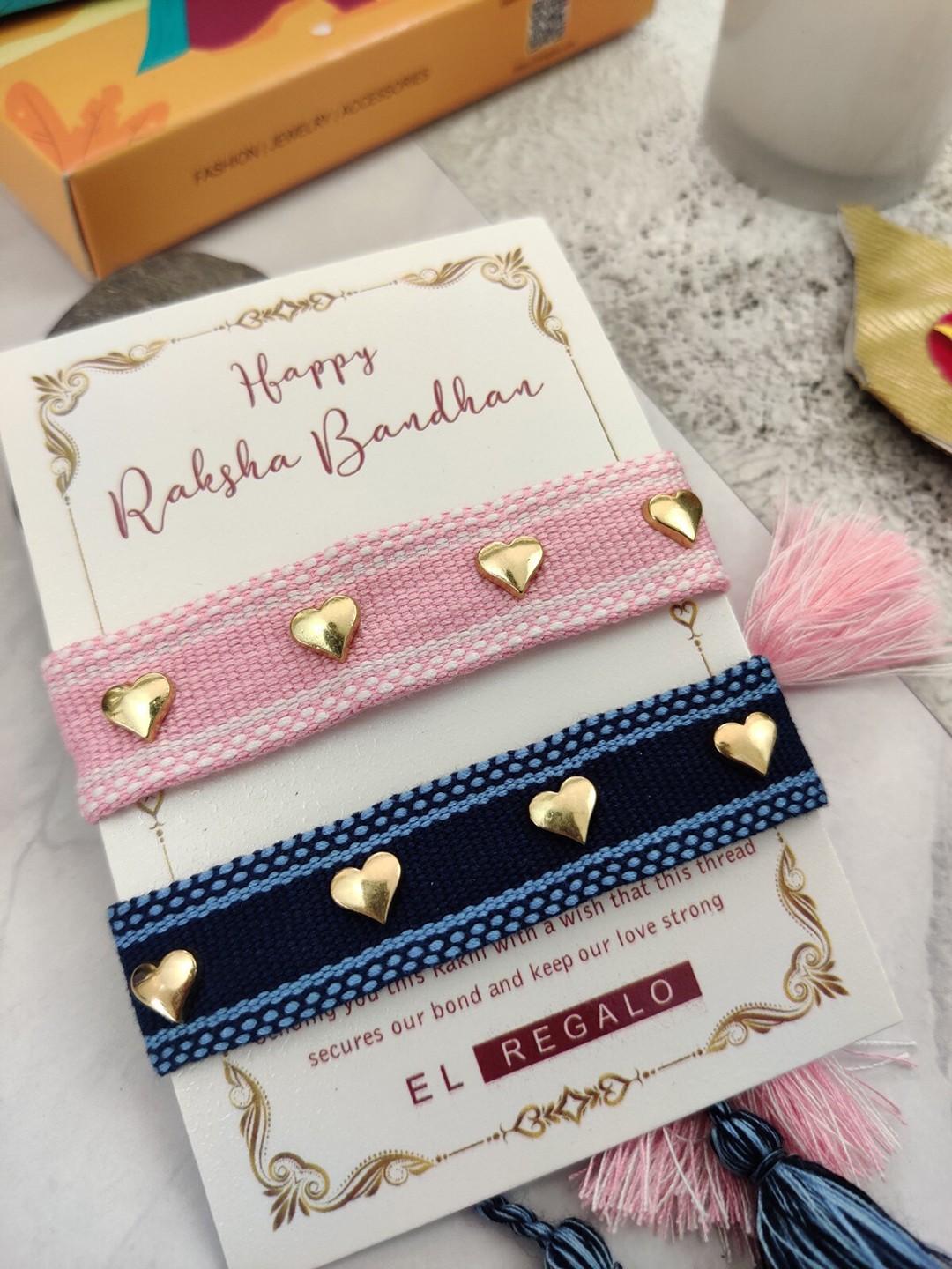 

EL REGALO Set Of 2 Heart Charm Rakhi With Candle & Greeting Card, Blue