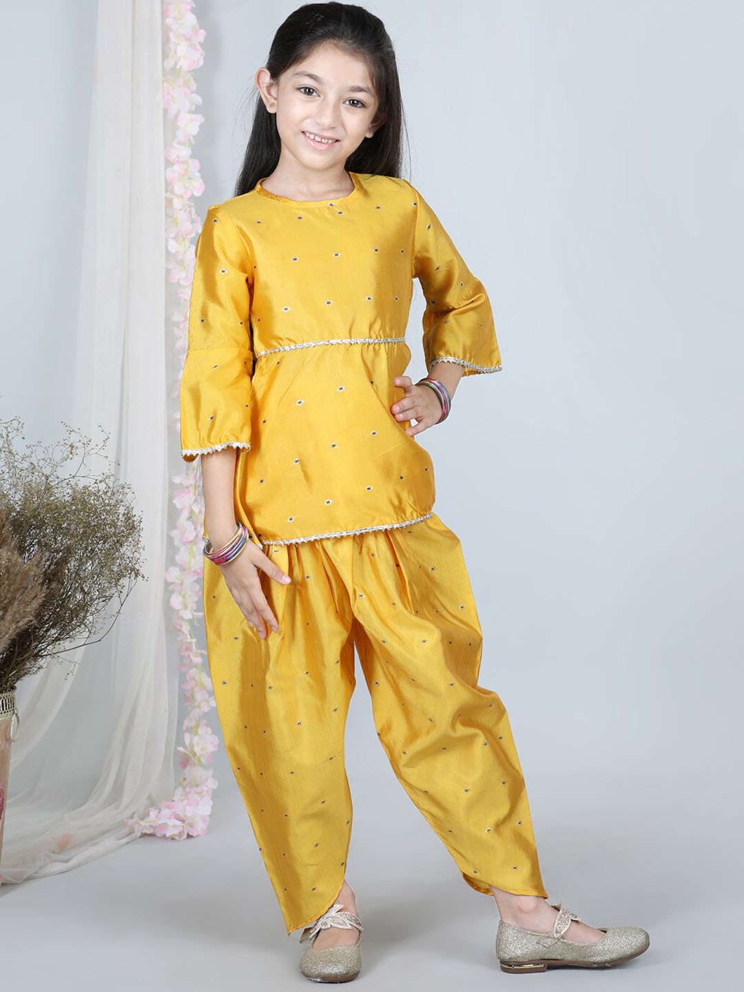 

Cutiekins Girls Round Neck Self Design Gotta Patti Bell Sleeve Kurta with Dhoti Pants, Mustard