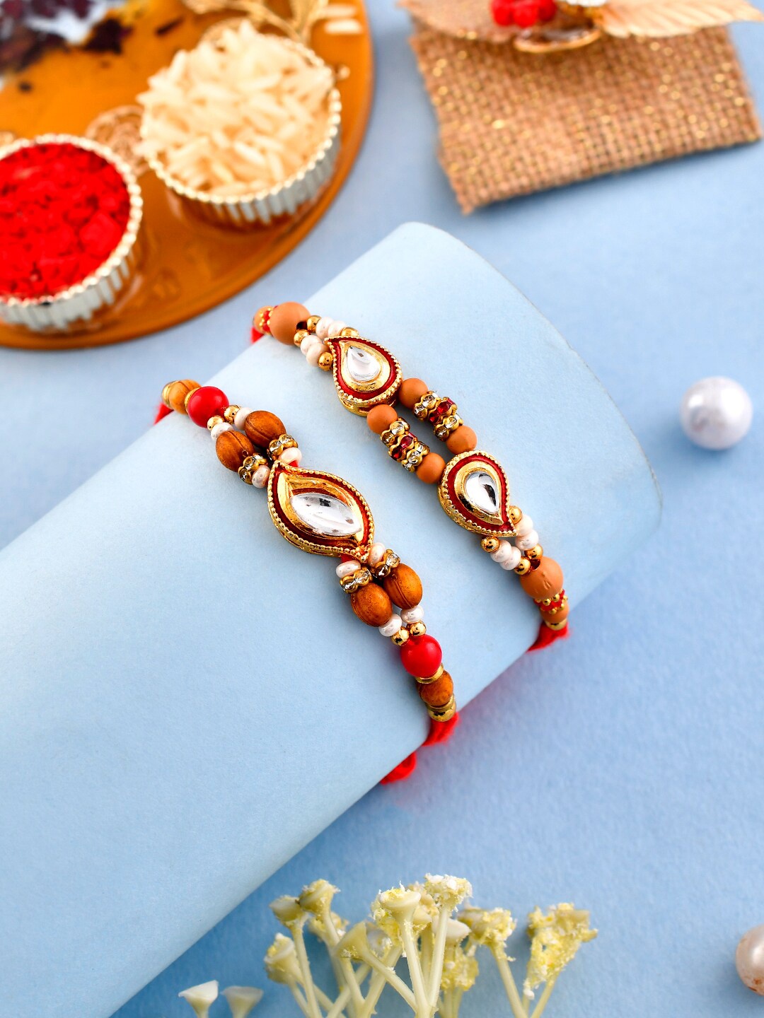 

Aapno Rajasthan Unisex Set Of 2 Stone-Studded Beaded Rakhis With Roli Rice & Greeting, Red