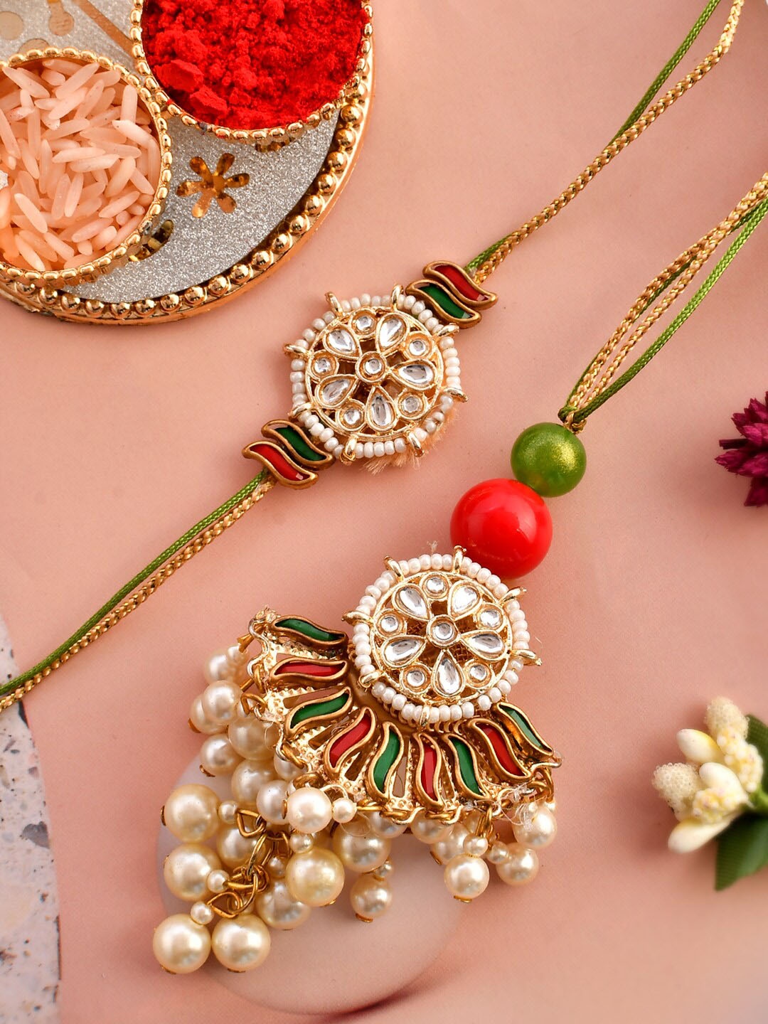 

Aapno Rajasthan Set Of 2 Kundan & Pearl Rakhi With Roli Rice & Greeting Card, Red