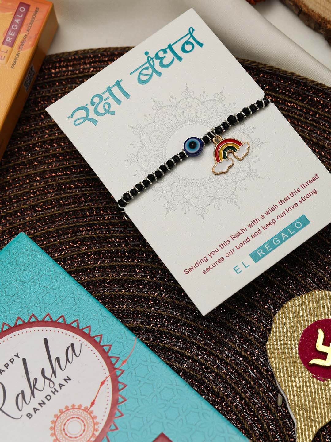 

EL REGALO Kids Evil Eye & Rainbow Charm Rakhi With Roli Chawl & Greeting Card, Black