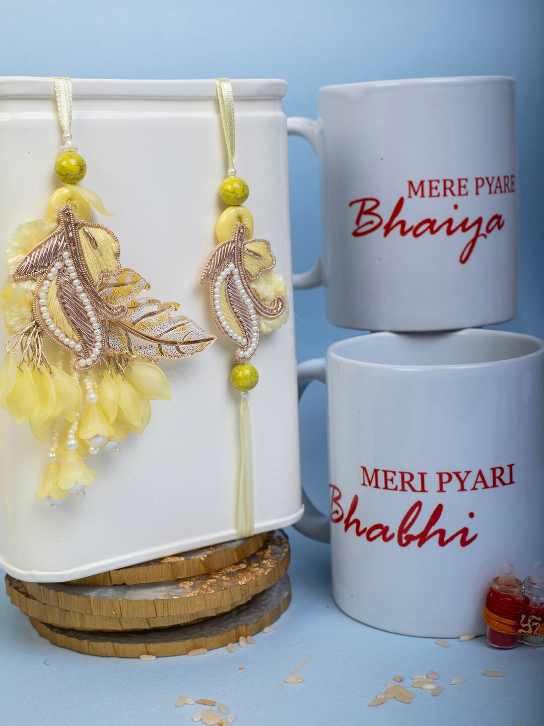 

PANASH Set Of 2 Feather Charm Rakhi with 2 Mugs Roli & Rice, Yellow