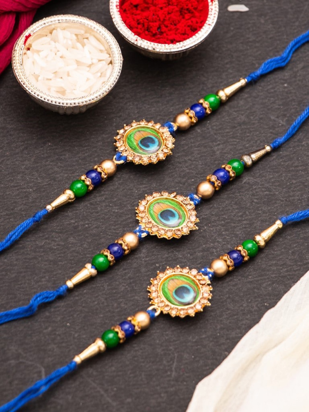 

CraftVatika Set Of 3 Peacock Feather Rakhis With Roli Chawal, Blue