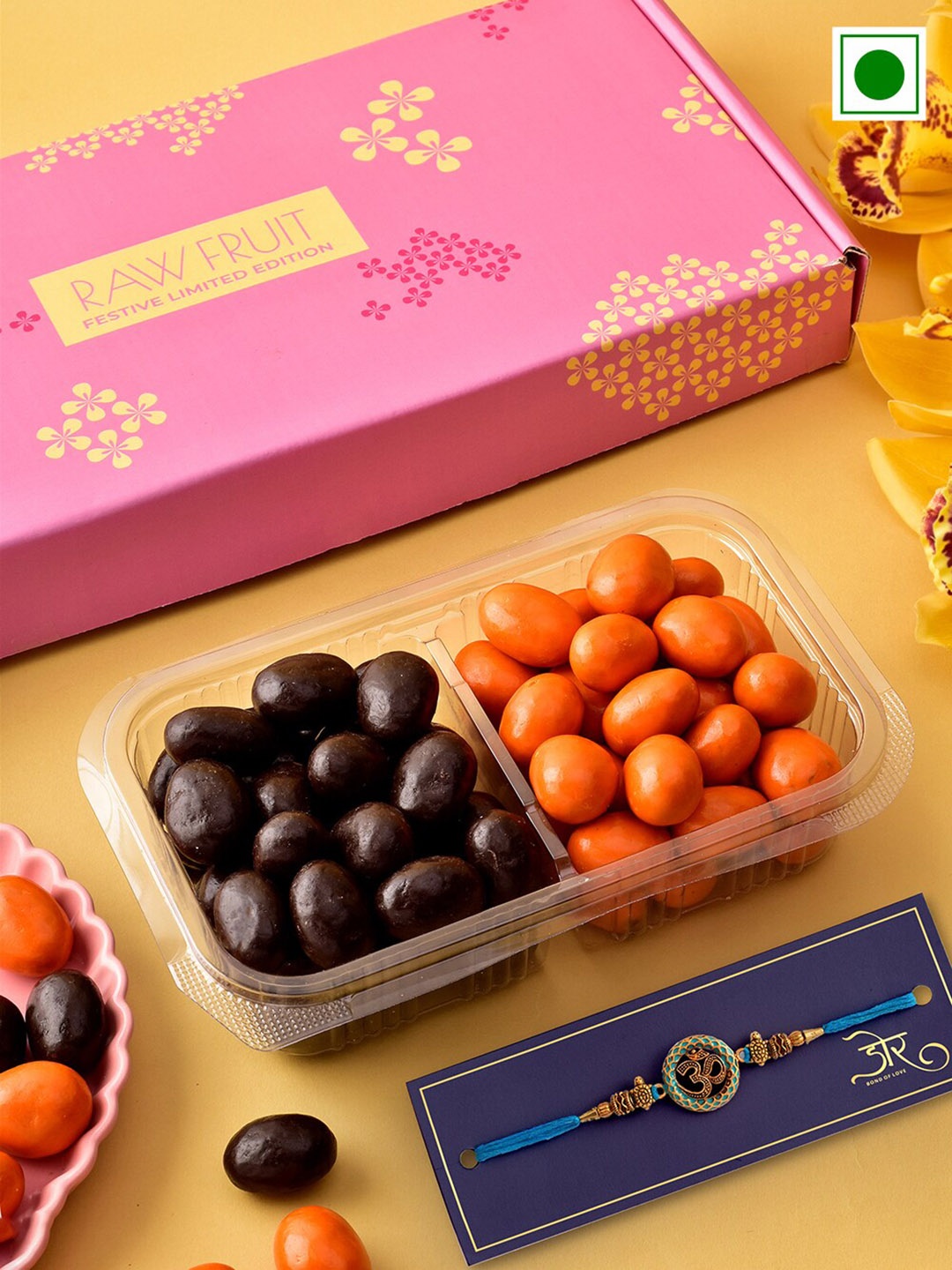 

RawFruit Om Charm Rakhi With Orange Dark Chocolate Dragees Gift Pack, Gold