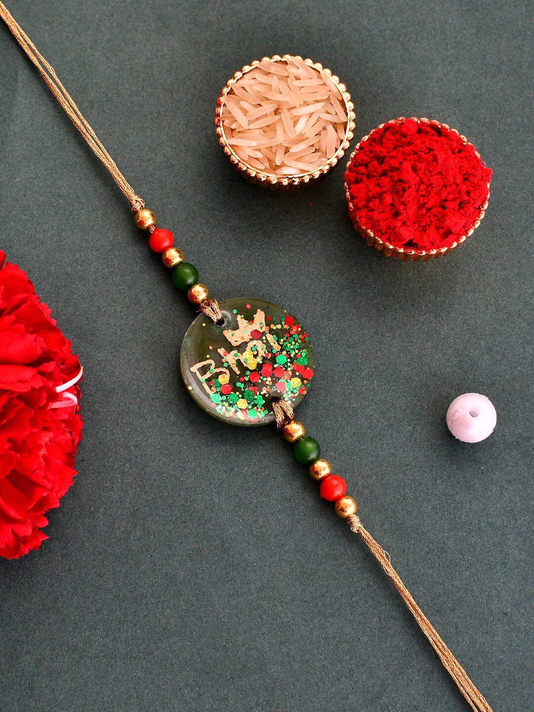 

Aapno Rajasthan Unisex Bhai Charm Rakhi With Greeting Card & Roli Chawal, Green