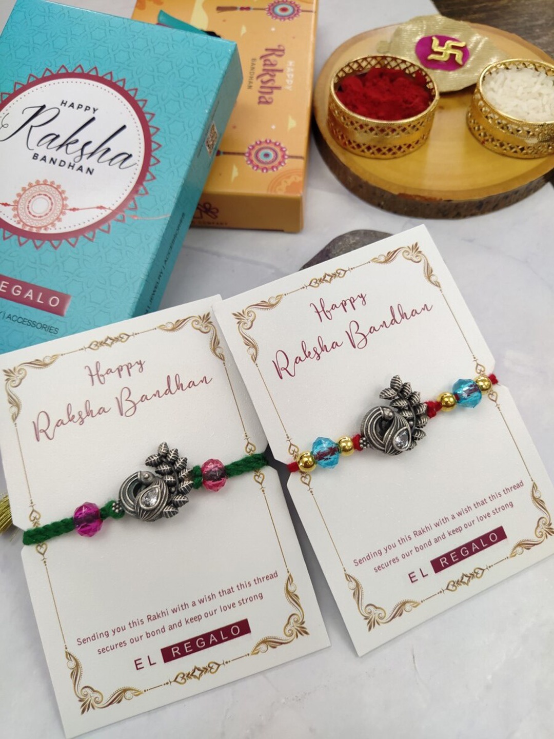 

EL REGALO Bhaiya Bhabhi Set Of 2 Charm Rakhi Combo With and Card, Roli Chawal, Red