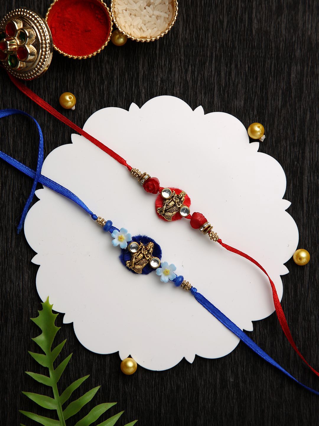 

Aapno Rajasthan Set Of 2 Radha Krishna Beaded Rakhis With Roli Chawal & Greeting Card, Red